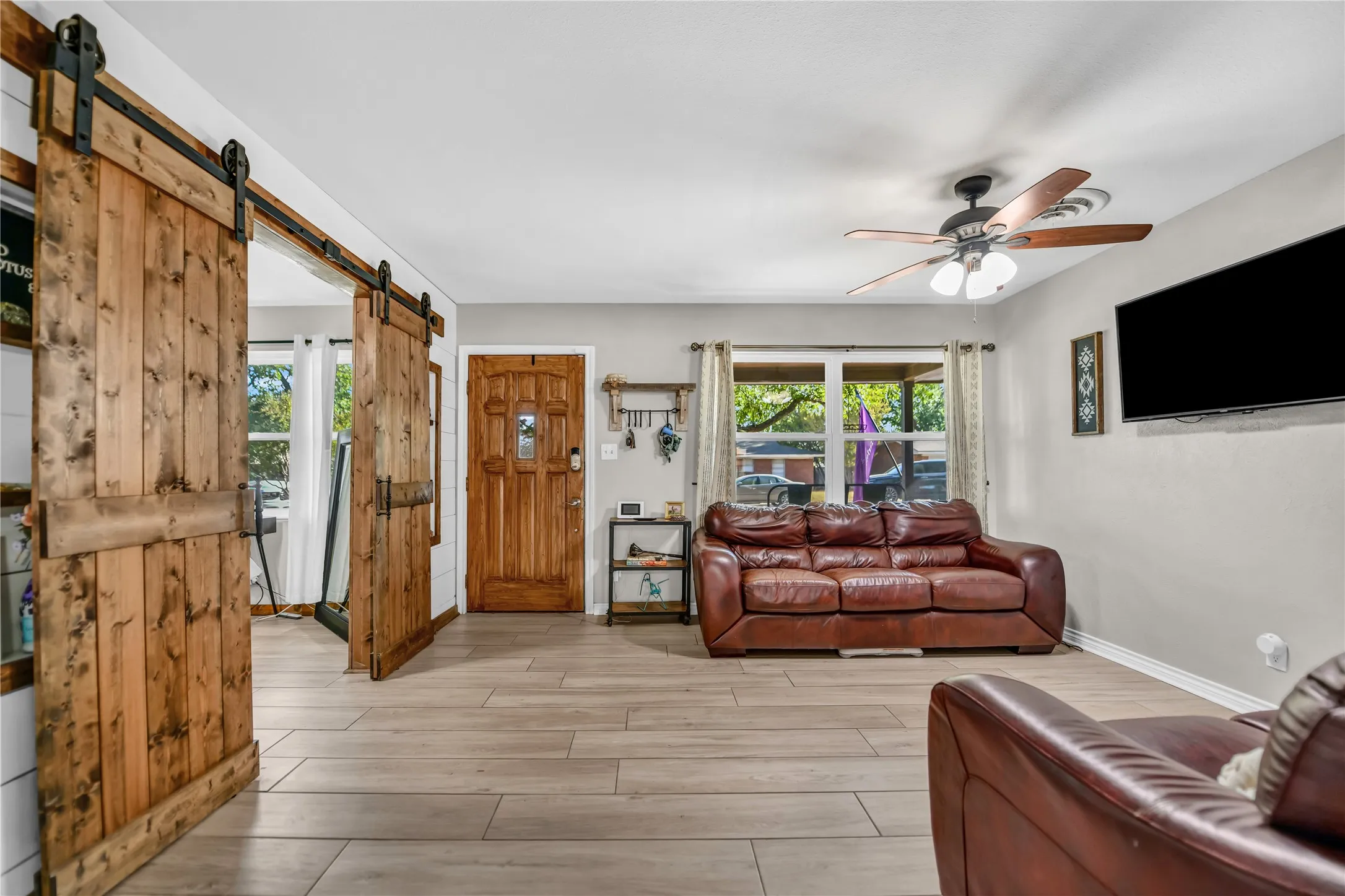 Wood-finish flooring throughout, complemented by a wood-paneled entry door, and wood-finish ceiling fan