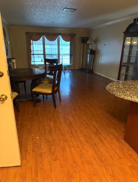 Wood-finish flooring throughout, crown molding, and a built-in breakfast bar with a stone-finish countertop