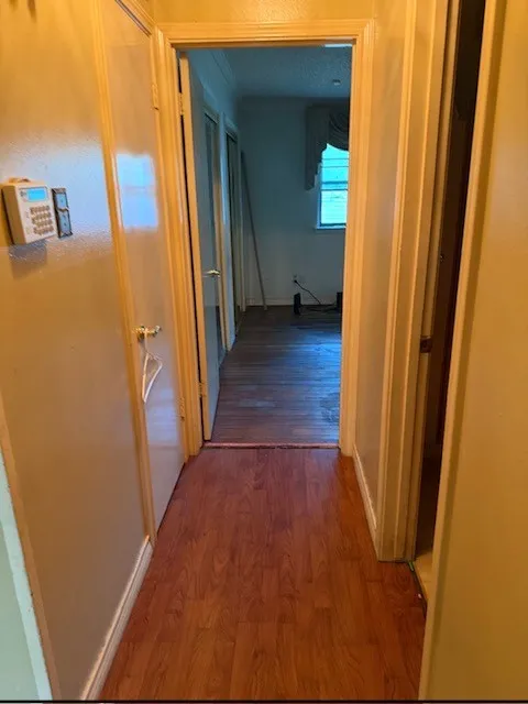 Wood-finish flooring throughout the hallway and room beyond