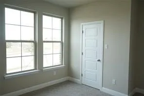 Neutral wall finish, white trim, carpeted flooring, and a white paneled door
