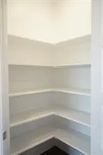Built-in shelving with multiple levels, white finishes, and dark flooring