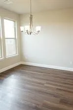 Wood-finish flooring, multiple windows, and a multi-arm chandelier