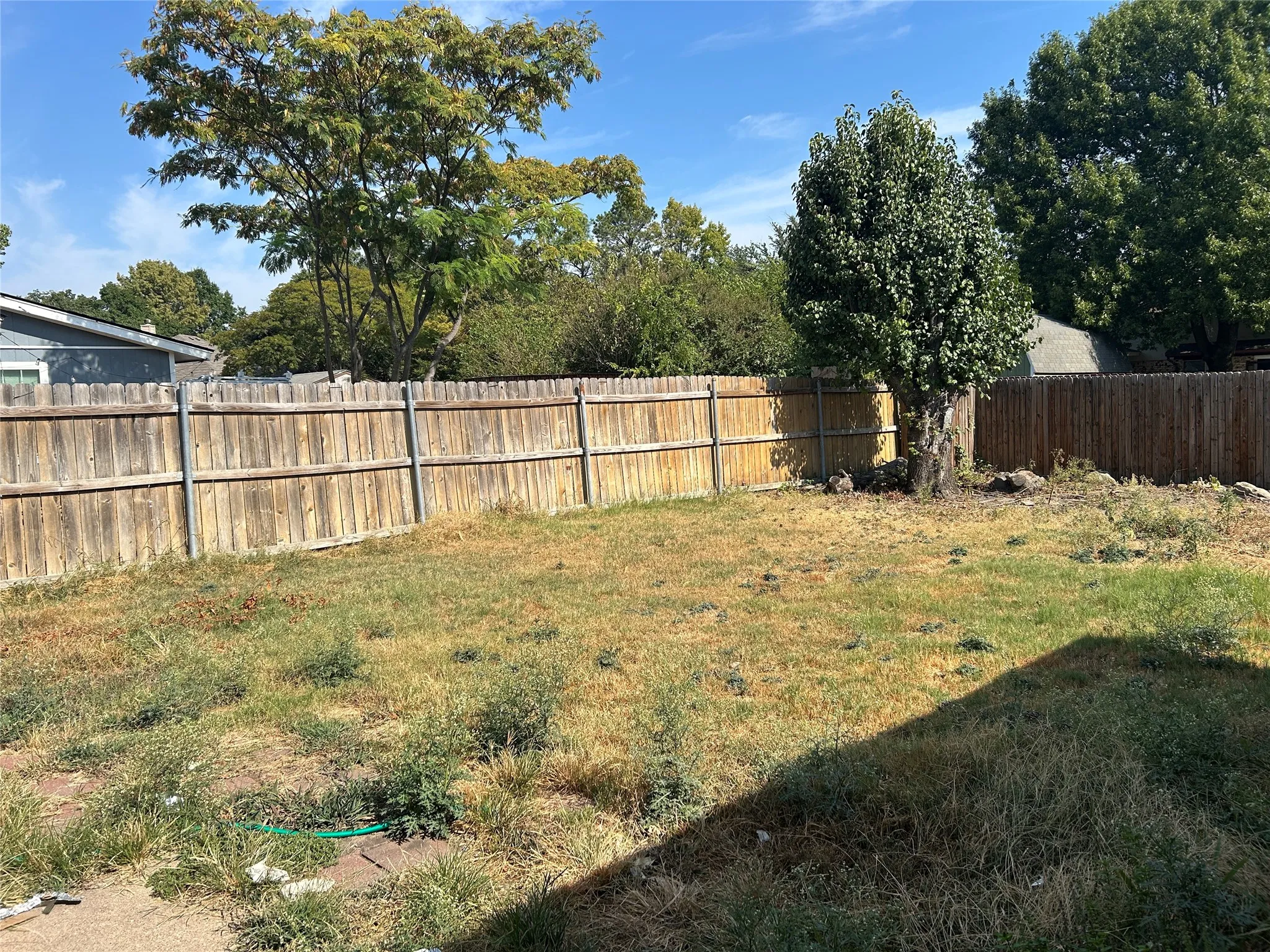 Expansive yard space featuring wood panel fencing and mature trees