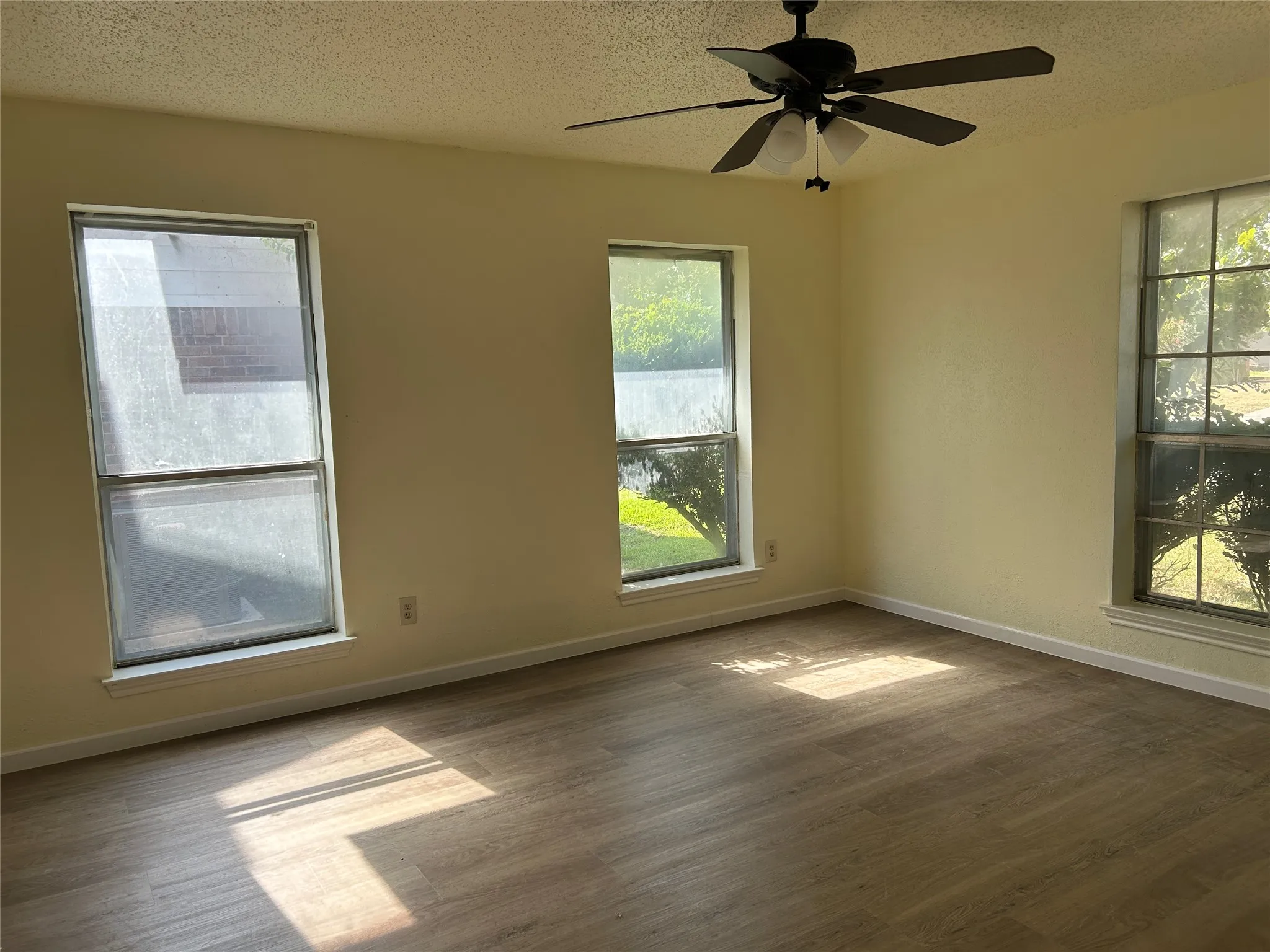 Wood-finish flooring, multiple windows, ceiling fan with integrated lighting
