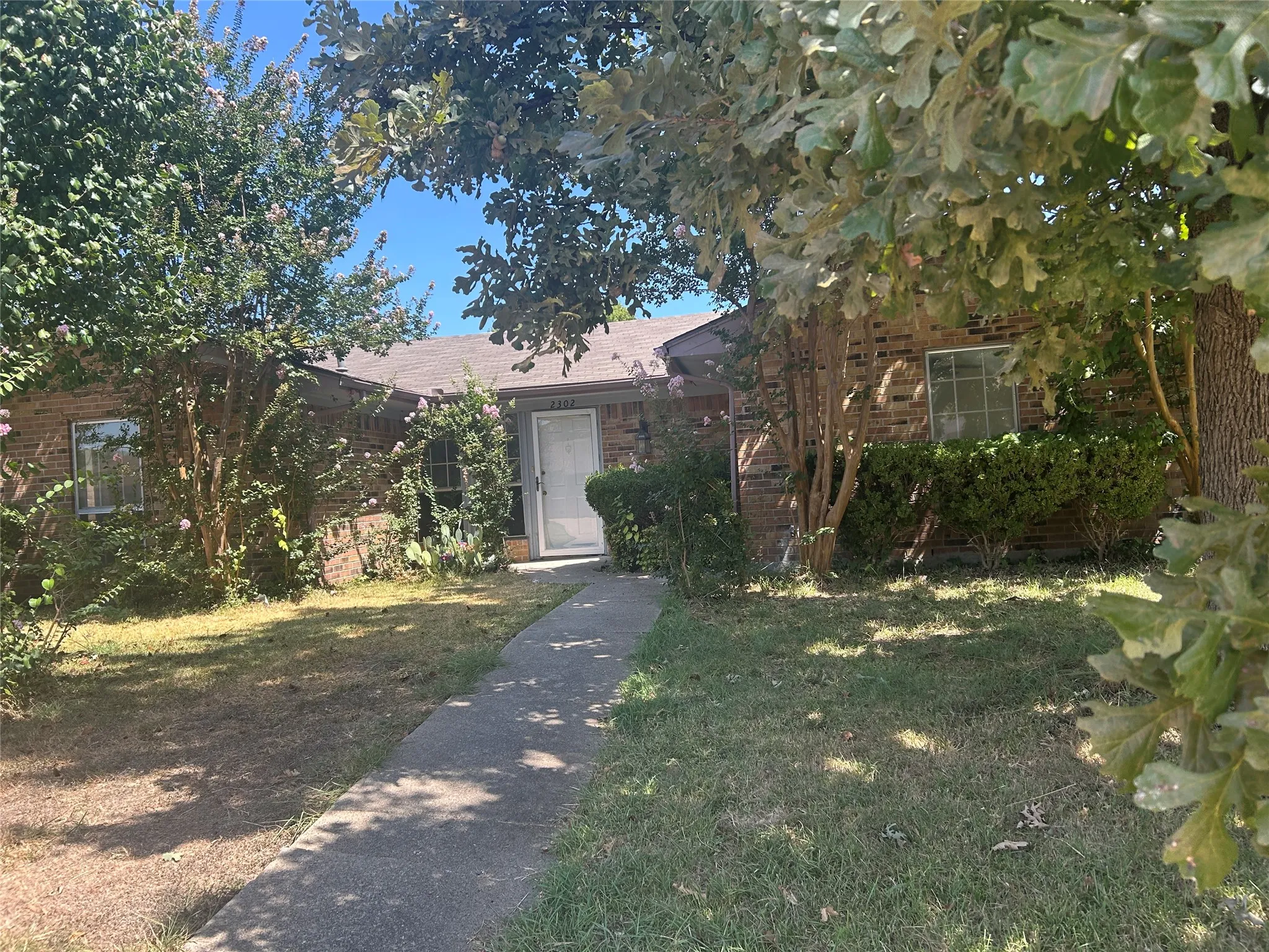 Brick exterior with mature trees and established landscaping