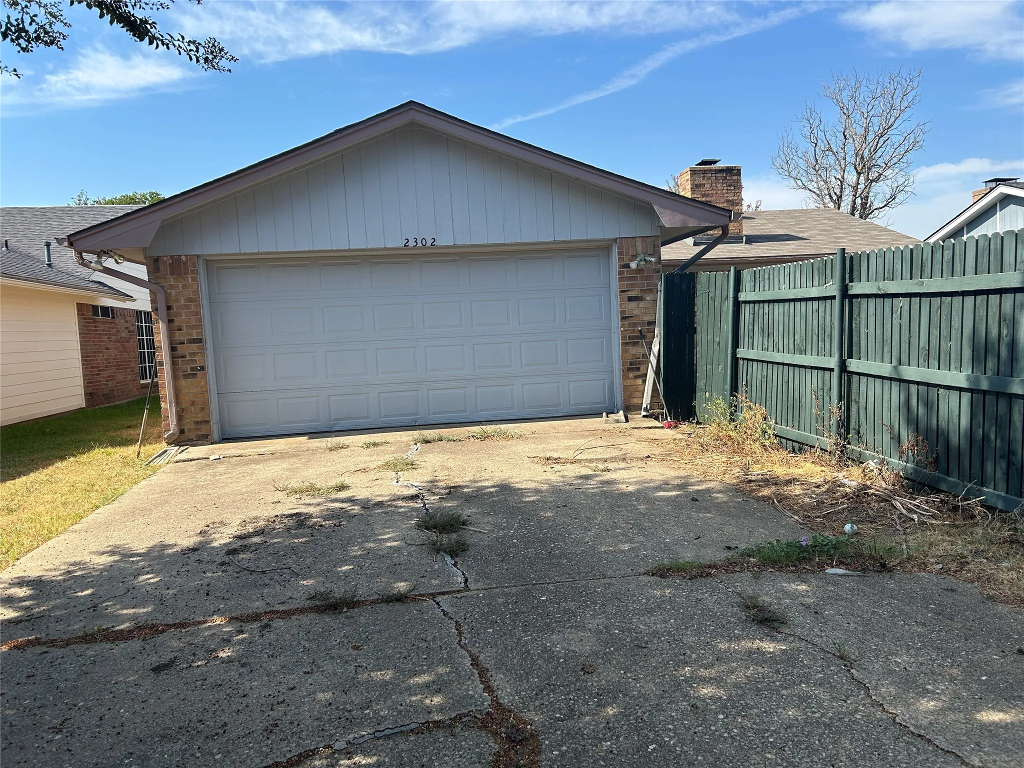Attached garage with a panel door, brick facade, and a shingled roof