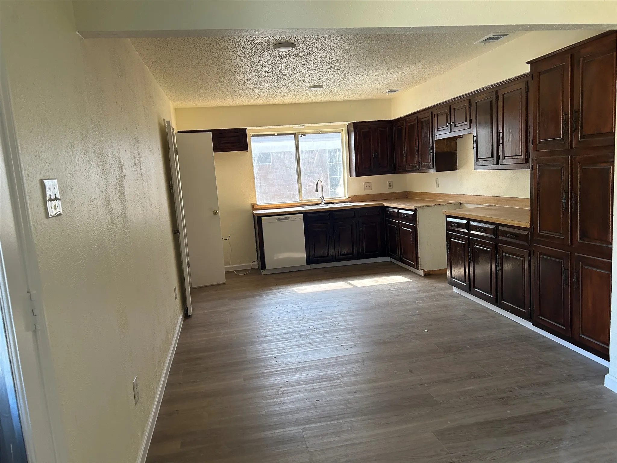 Kitchen featuring extensive dark wood-finish cabinetry, wood-finish countertops, wood-finish flooring, and a stainless steel sink with a gooseneck faucet