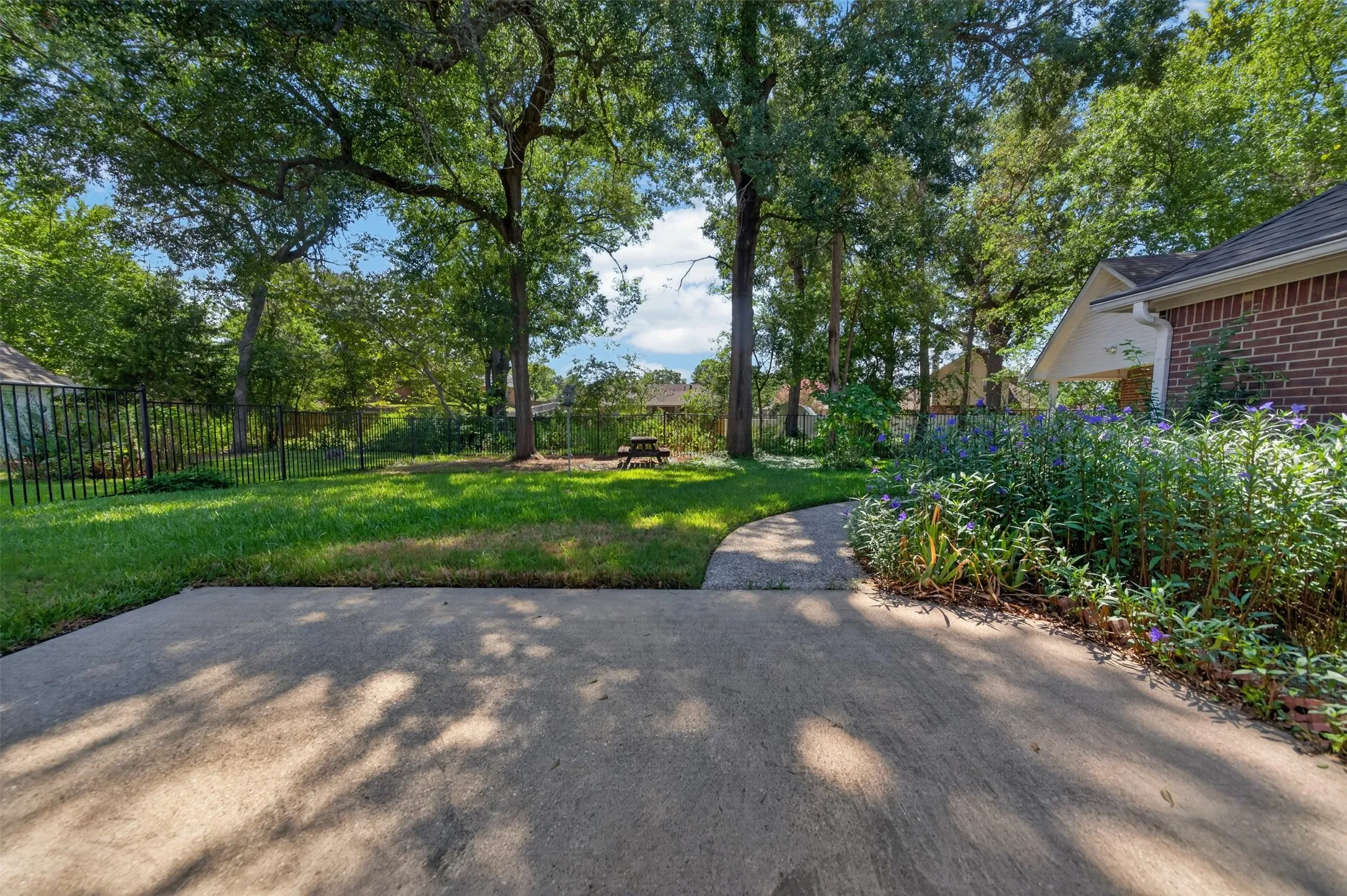 Taken from the Back Patio out over the Backyard.  Walkway to Workshop, This area is where the iron fencing is not on the actual property line on what would be the West side.  (Left side when looking out from the patio)