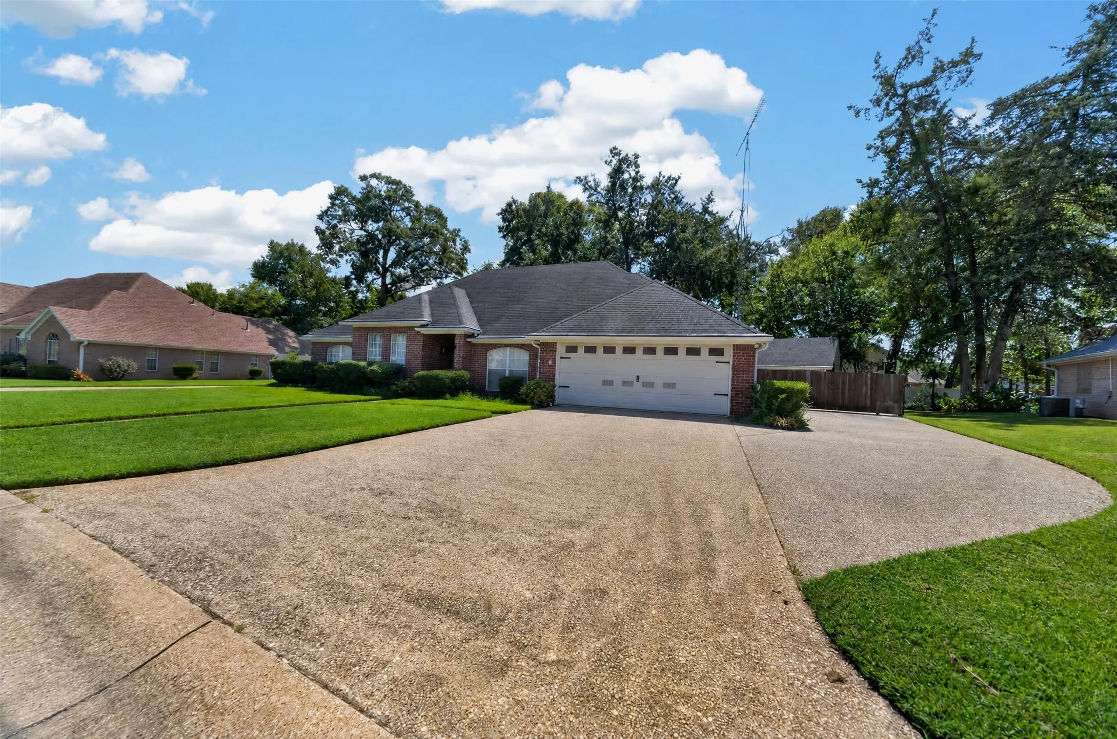 View of the Front showing the extra parking area and entrance to the backyard where you could park an RV between the home and workshop.  There is a large gate at entrance.