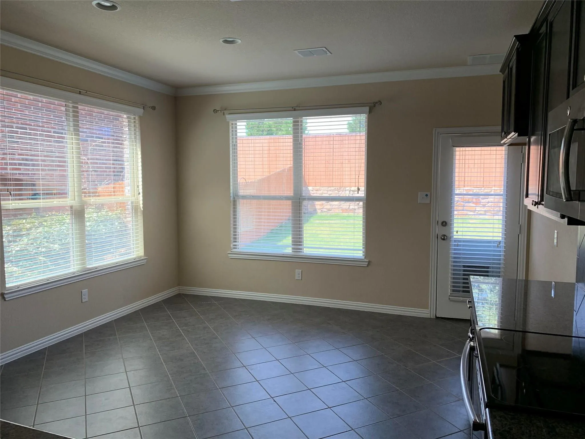 Tile flooring, recessed lighting, crown molding, multiple windows with blinds, and exterior door access