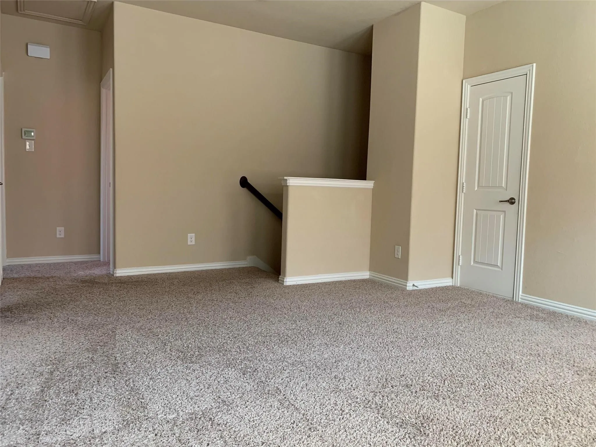 Spacious carpeted area with neutral wall tones and white trim