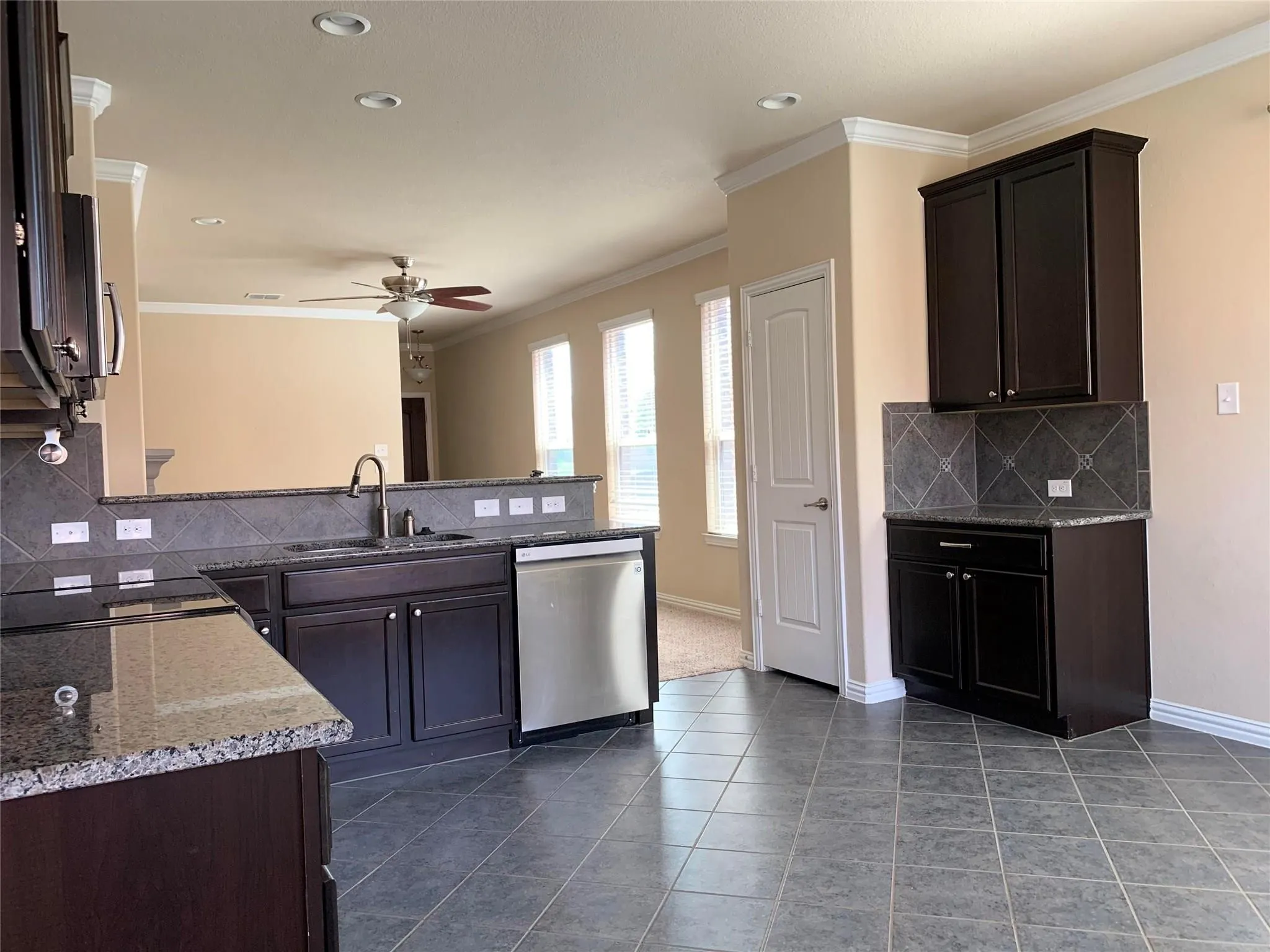 Kitchen featuring dark wood-finish cabinetry, granite countertops, stainless steel dishwasher, tile flooring, and recessed lighting