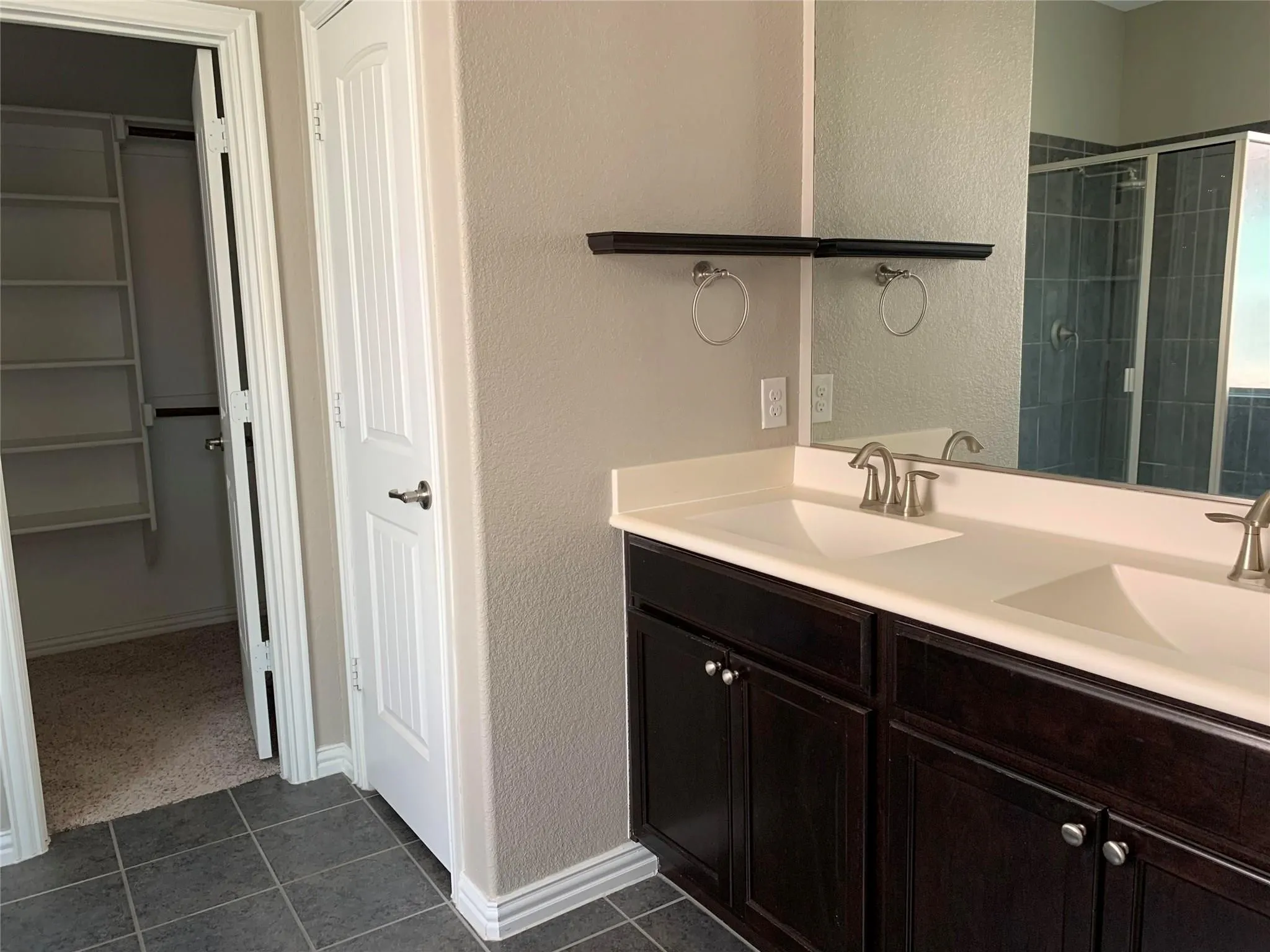 Dual vanity with white undermount sinks, dark wood-finish cabinetry, and a large mirror