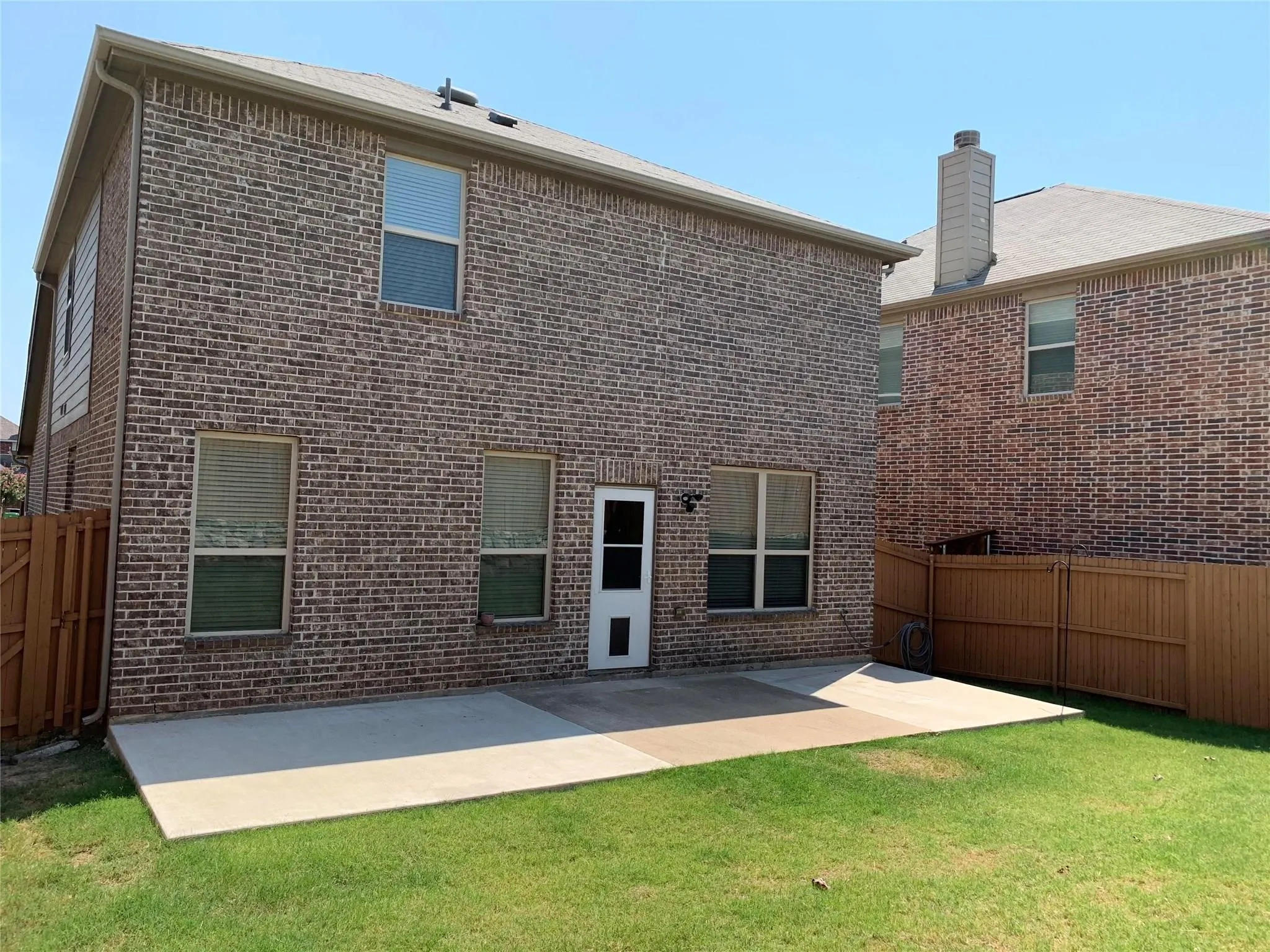 Brick exterior with a concrete patio and a manicured lawn