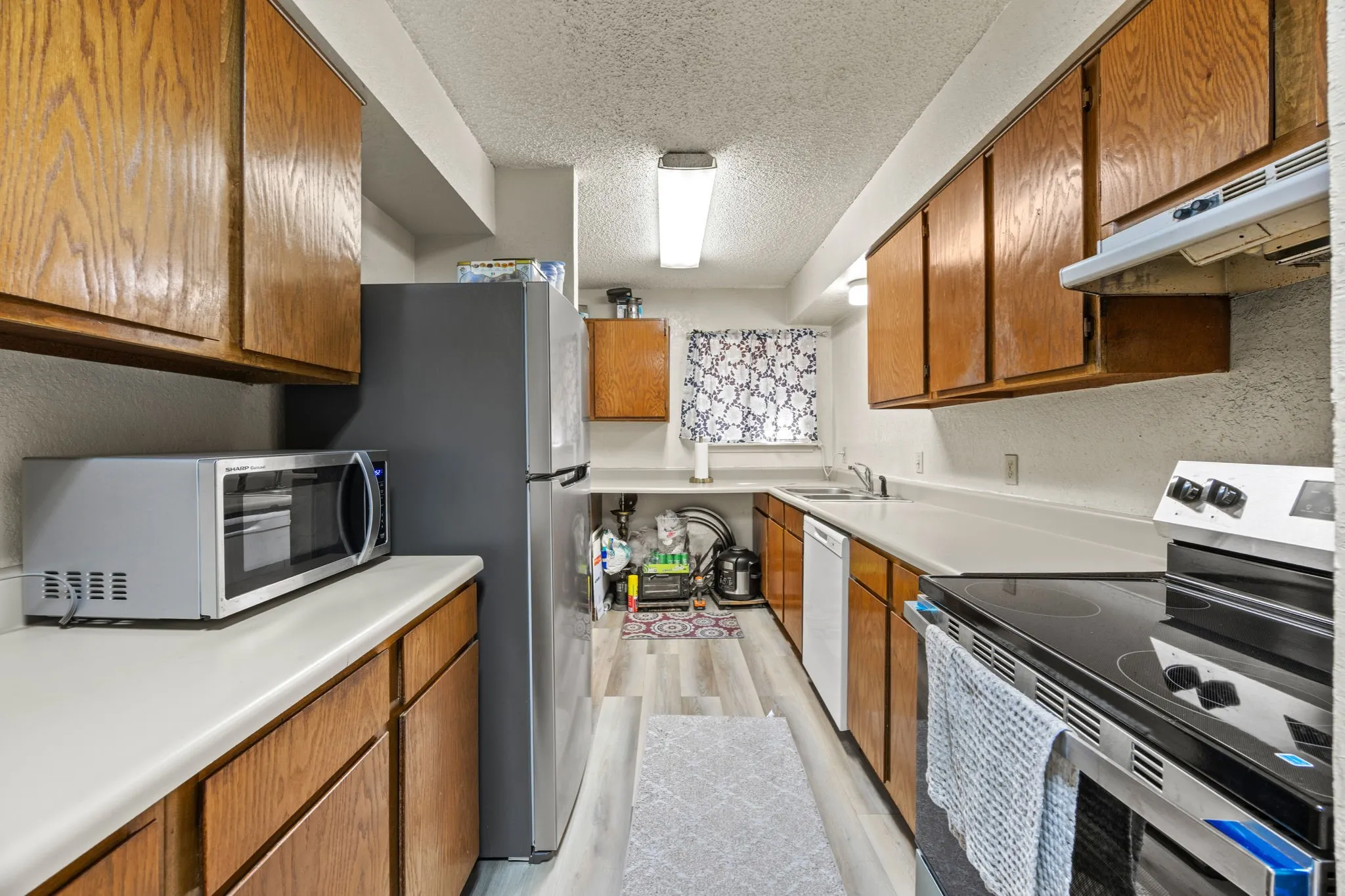 Galley kitchen featuring wood cabinetry, light-toned countertops, and wood-finish flooring