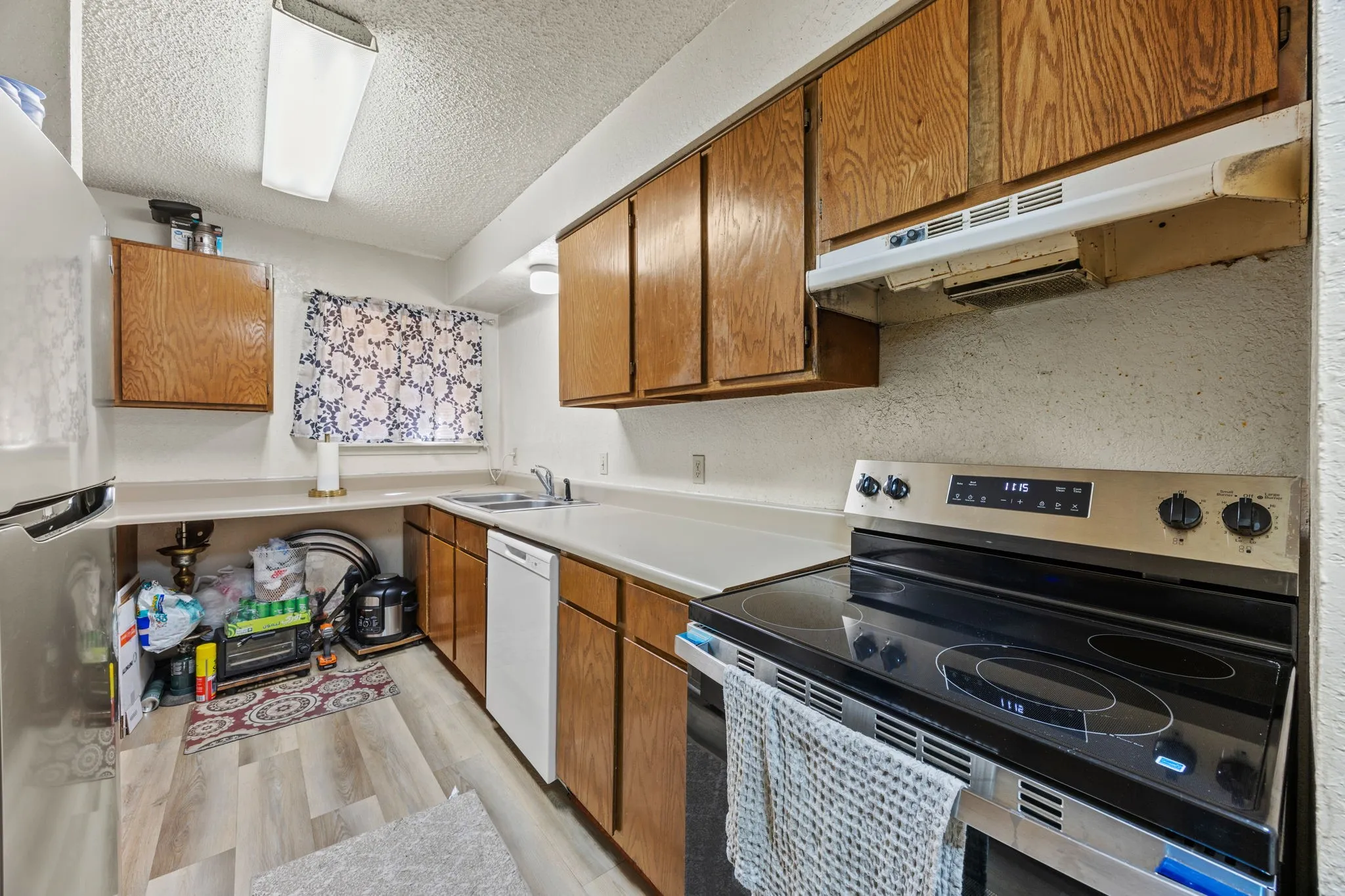 Kitchen featuring wood-finish cabinetry, solid surface countertops, a stainless steel range, and a built-in​​‌​​​​‌​​‌‌​‌‌​​​‌‌​‌​‌​‌​​​‌​​ dishwasher