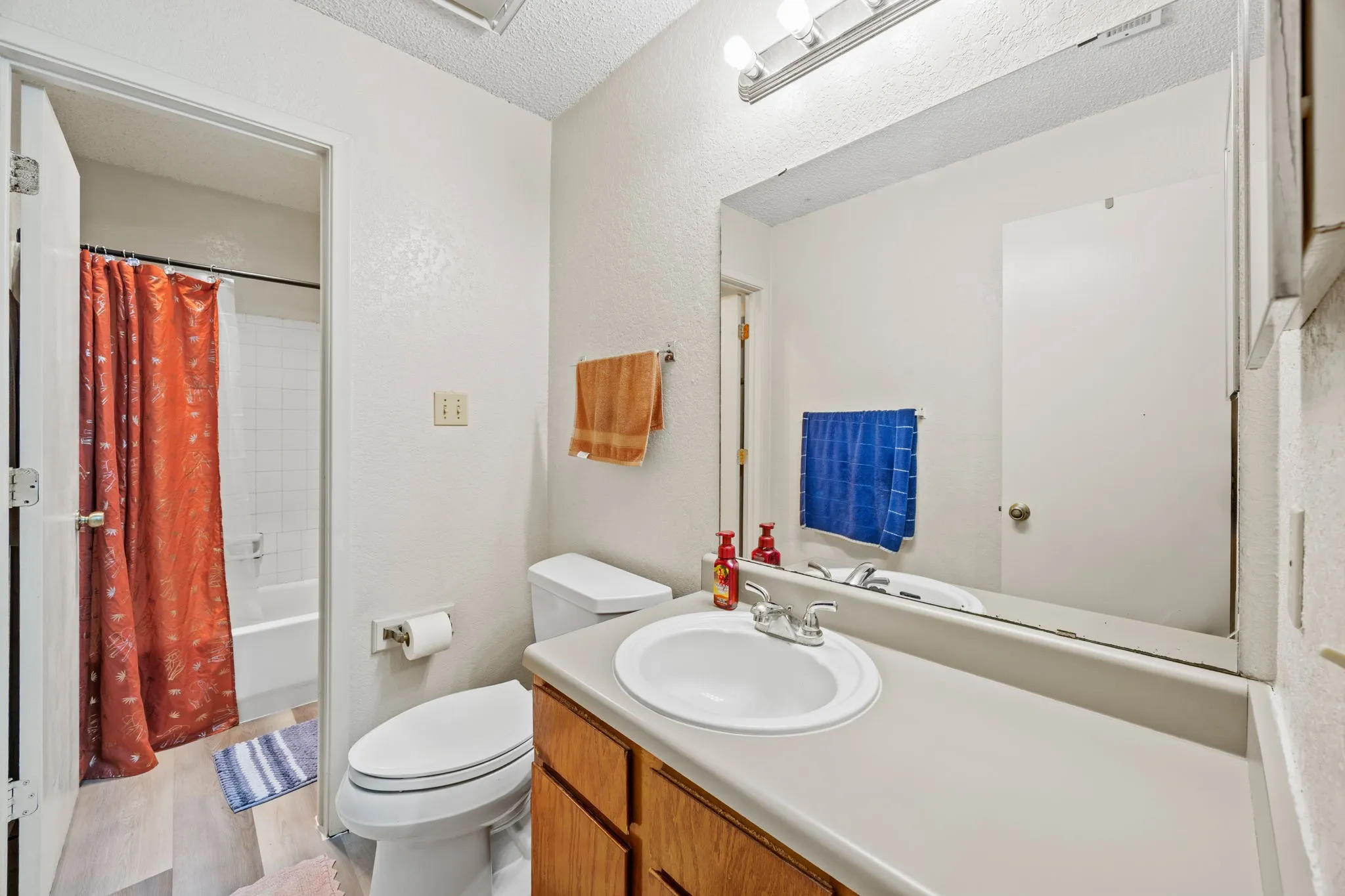 Vanity with integrated sink, wood-finish cabinetry, and overhead lighting