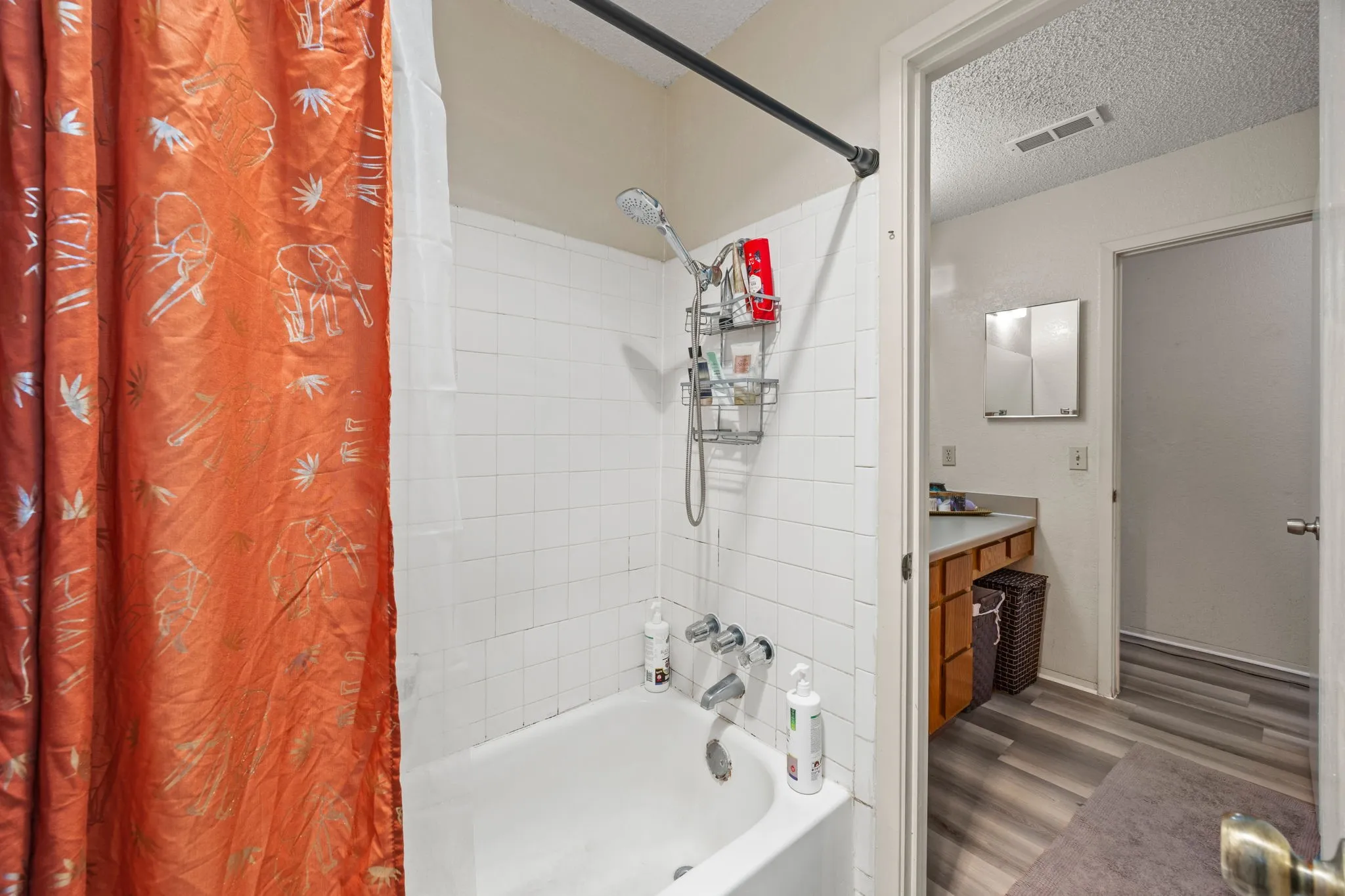 White tiled shower surround with a built-in tub and chrome fixtures