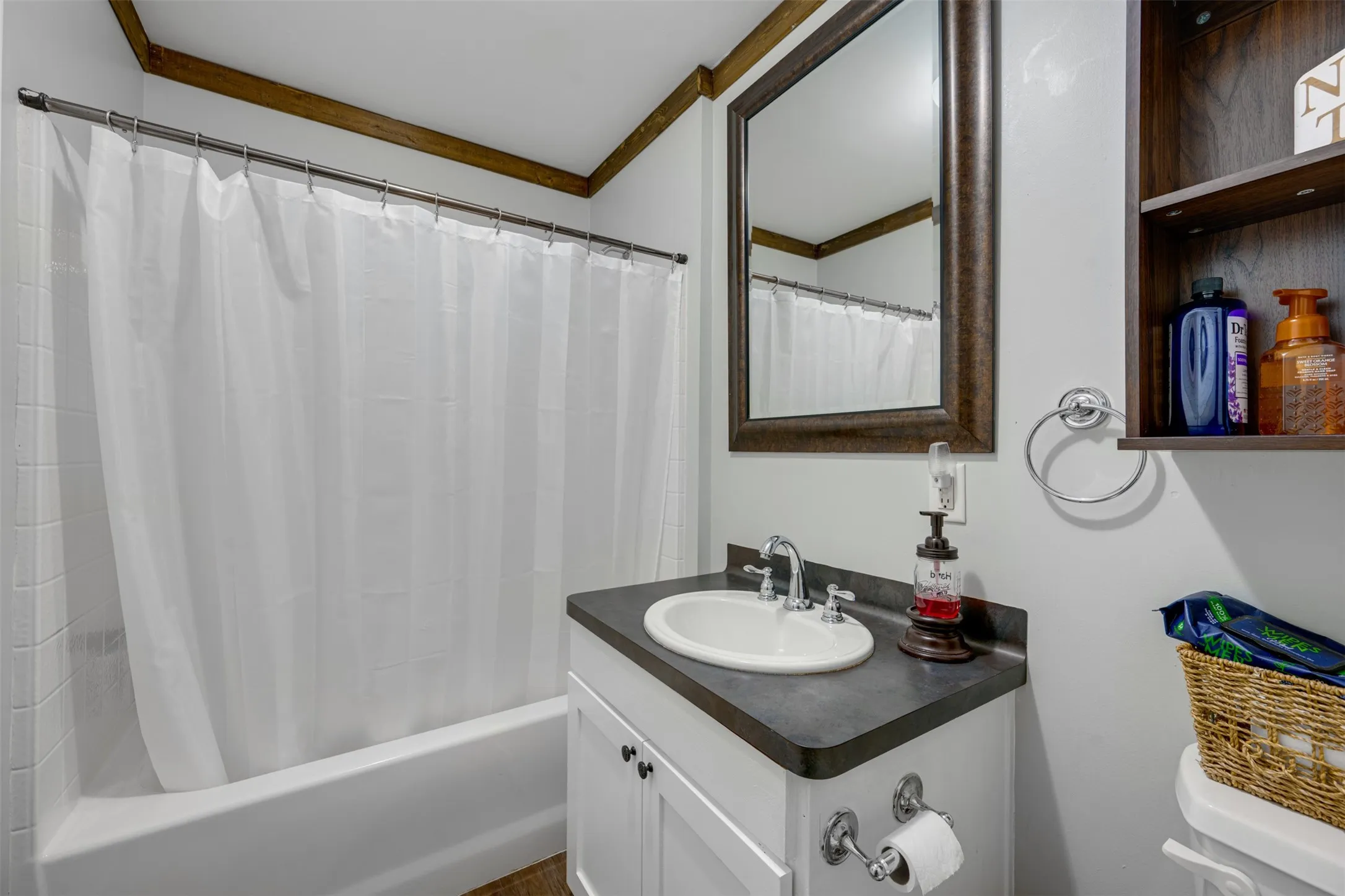 White vanity with a drop-in sink, dark countertop, and chrome faucet