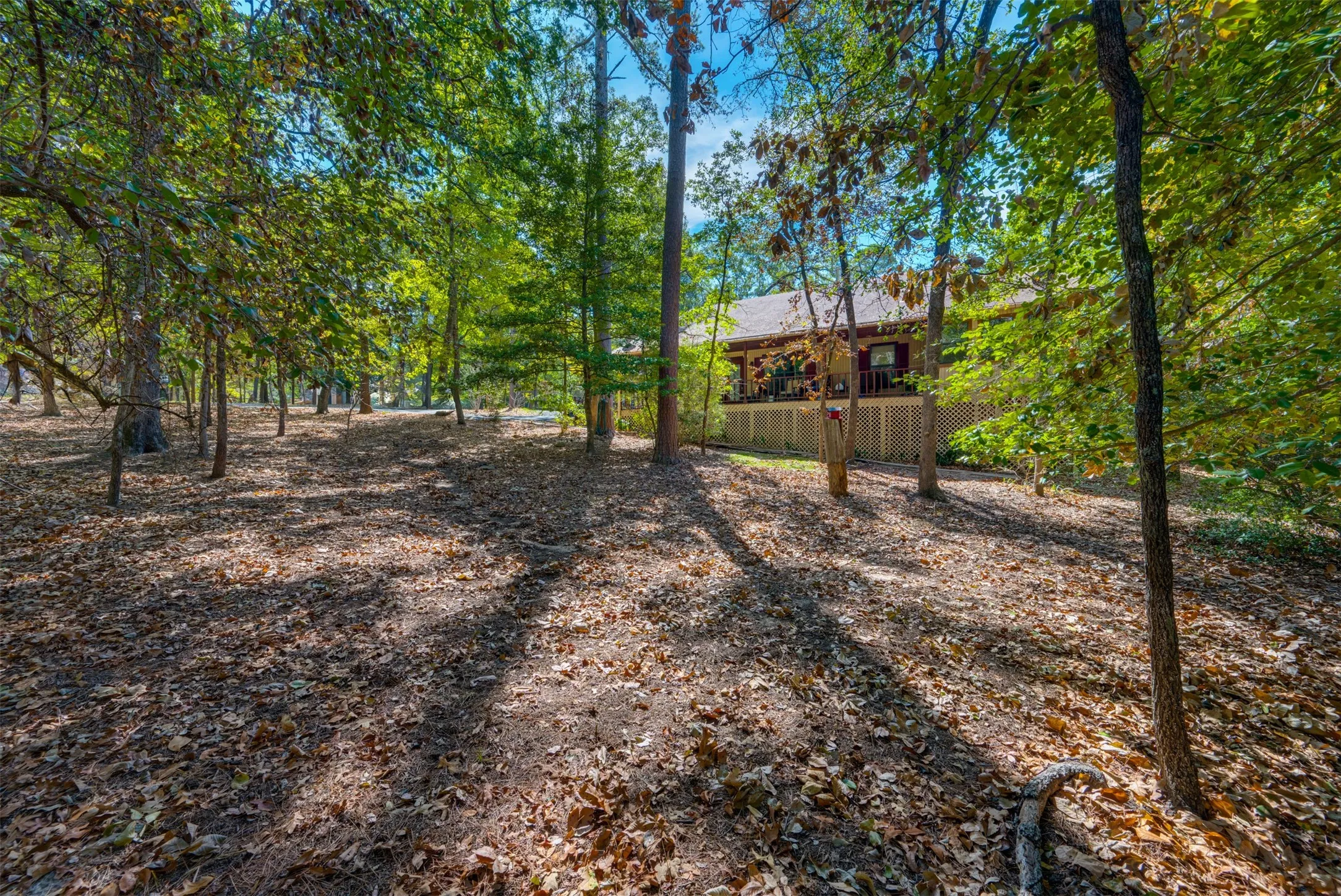 Wooded lot featuring mature trees and a private deck with lattice skirting