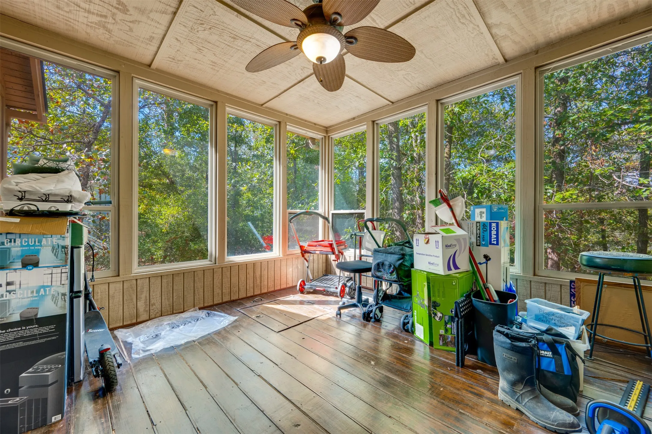 Sunroom with wood-finish flooring, paneled walls, a ceiling fan, and large windows
