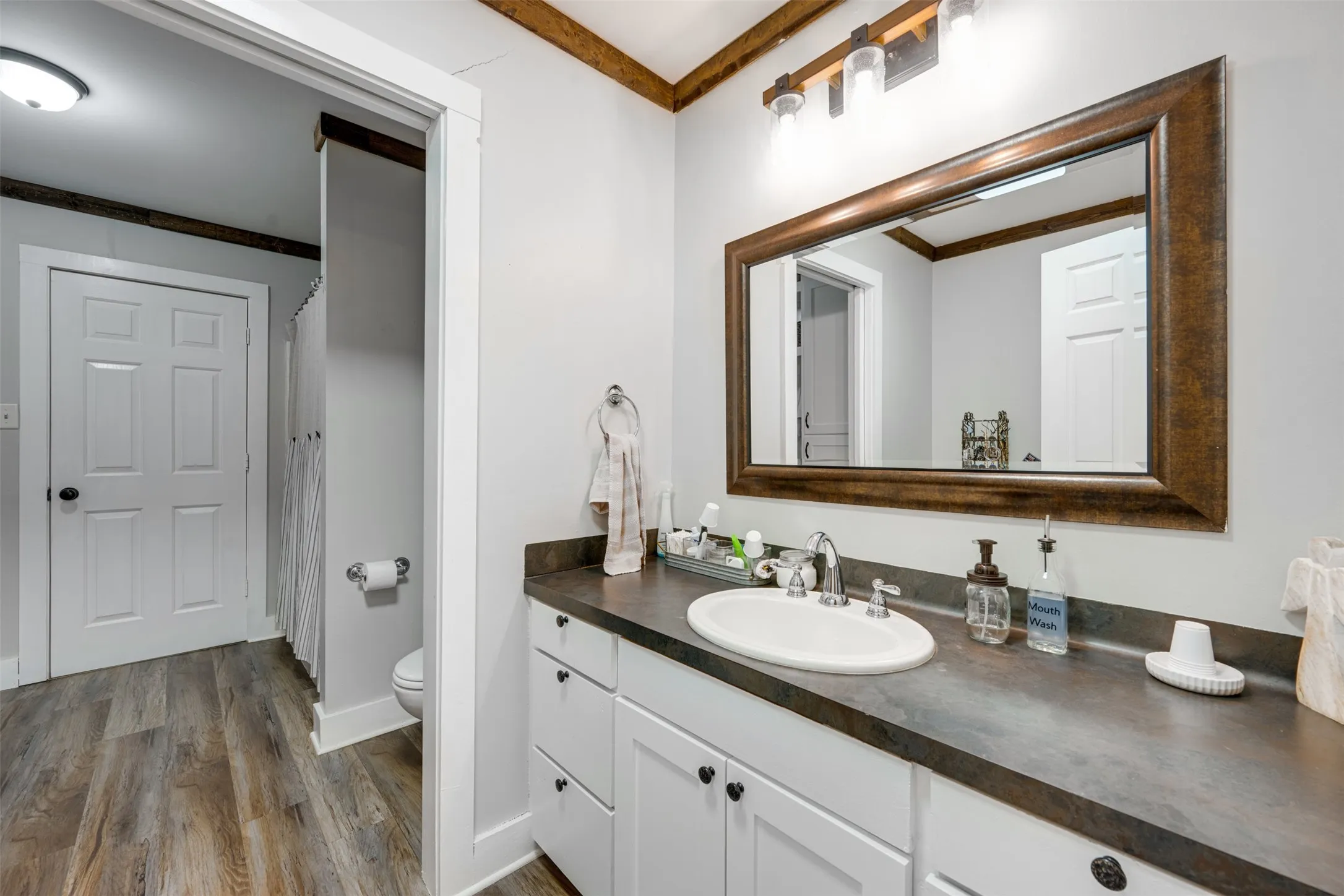 Vanity with an integrated sink, dark countertop, and white cabinetry