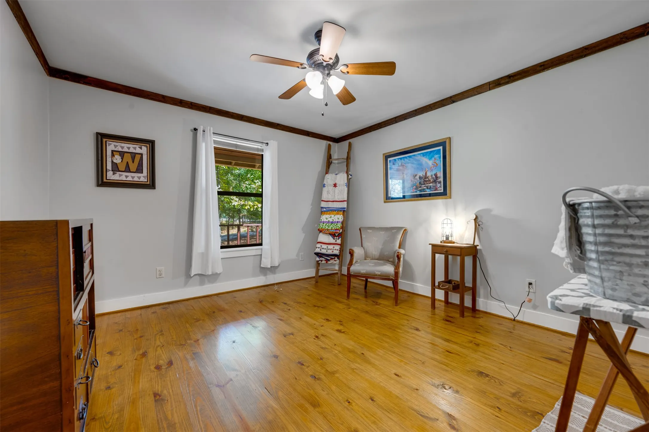 Hardwood flooring, painted walls, ceiling fan, crown molding, and a window with exterior views