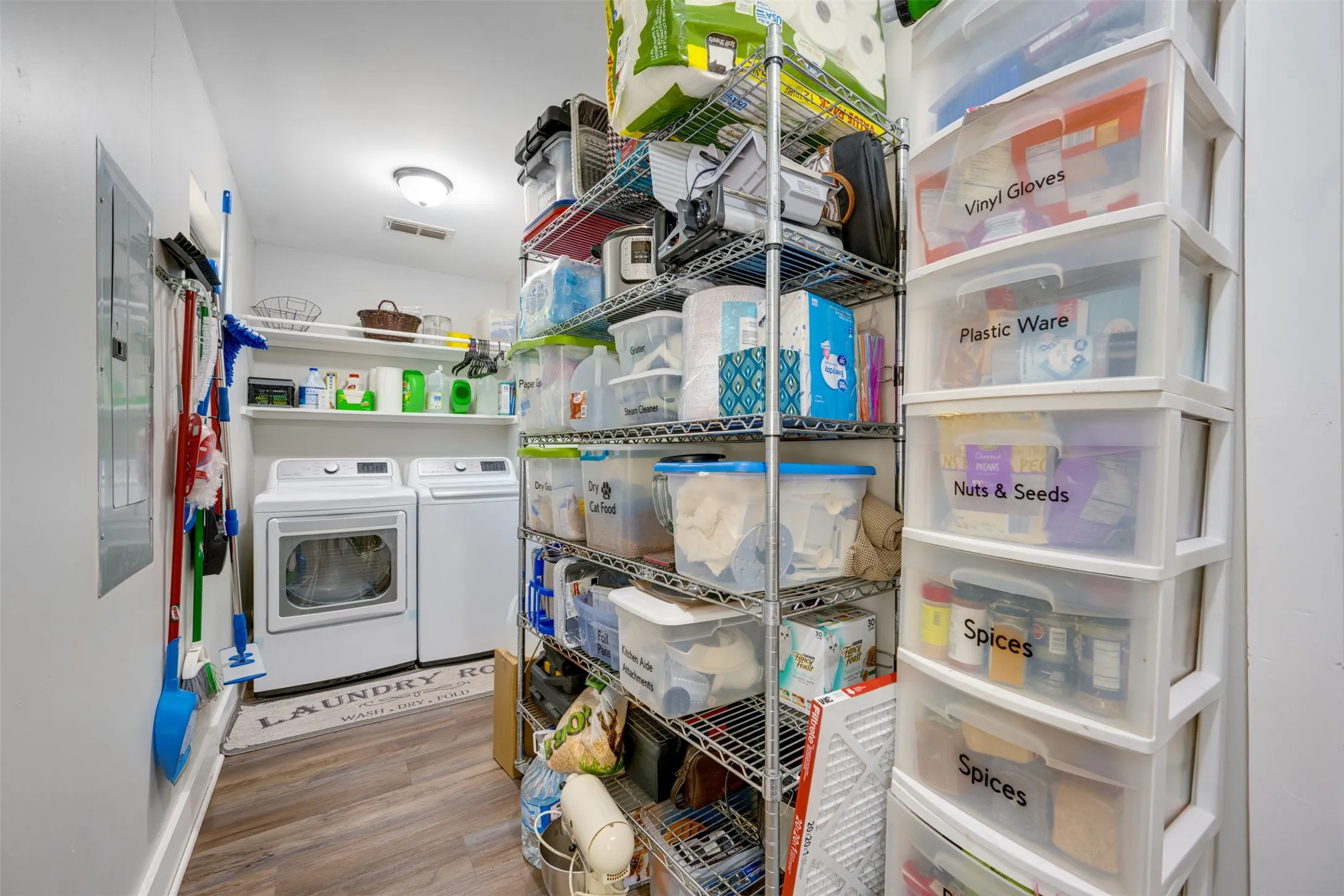 Laundry area featuring a side-by-side washer and dryer, wood-finish flooring, and overhead shelving