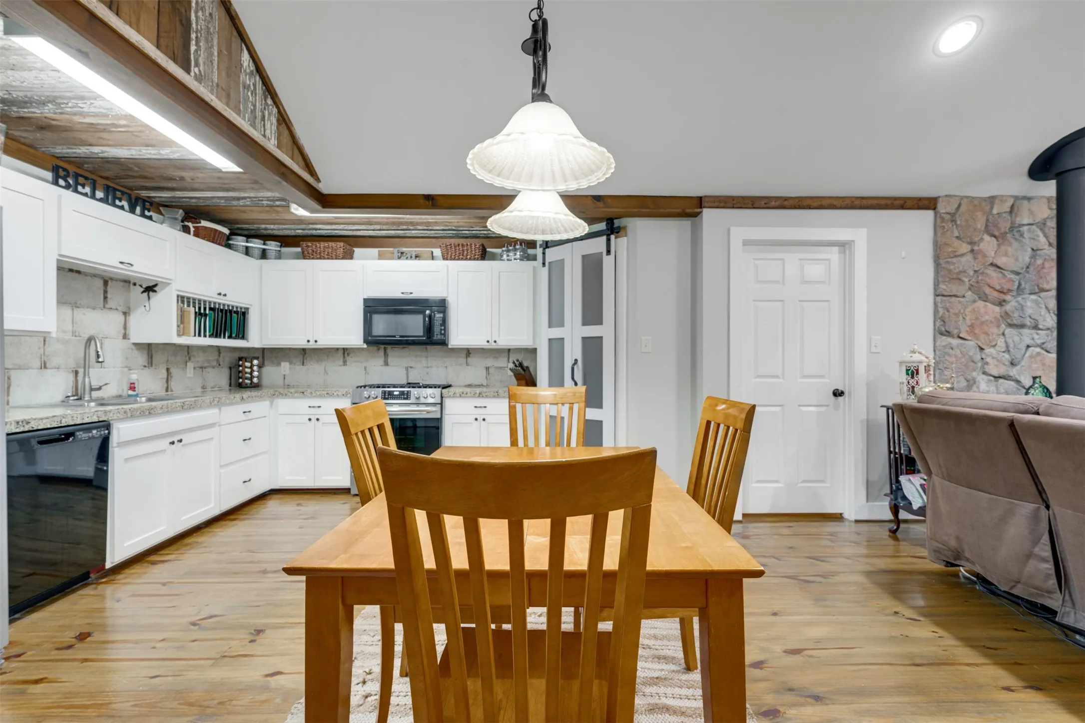 Open-concept living area featuring a kitchen with white cabinetry and dark appliances