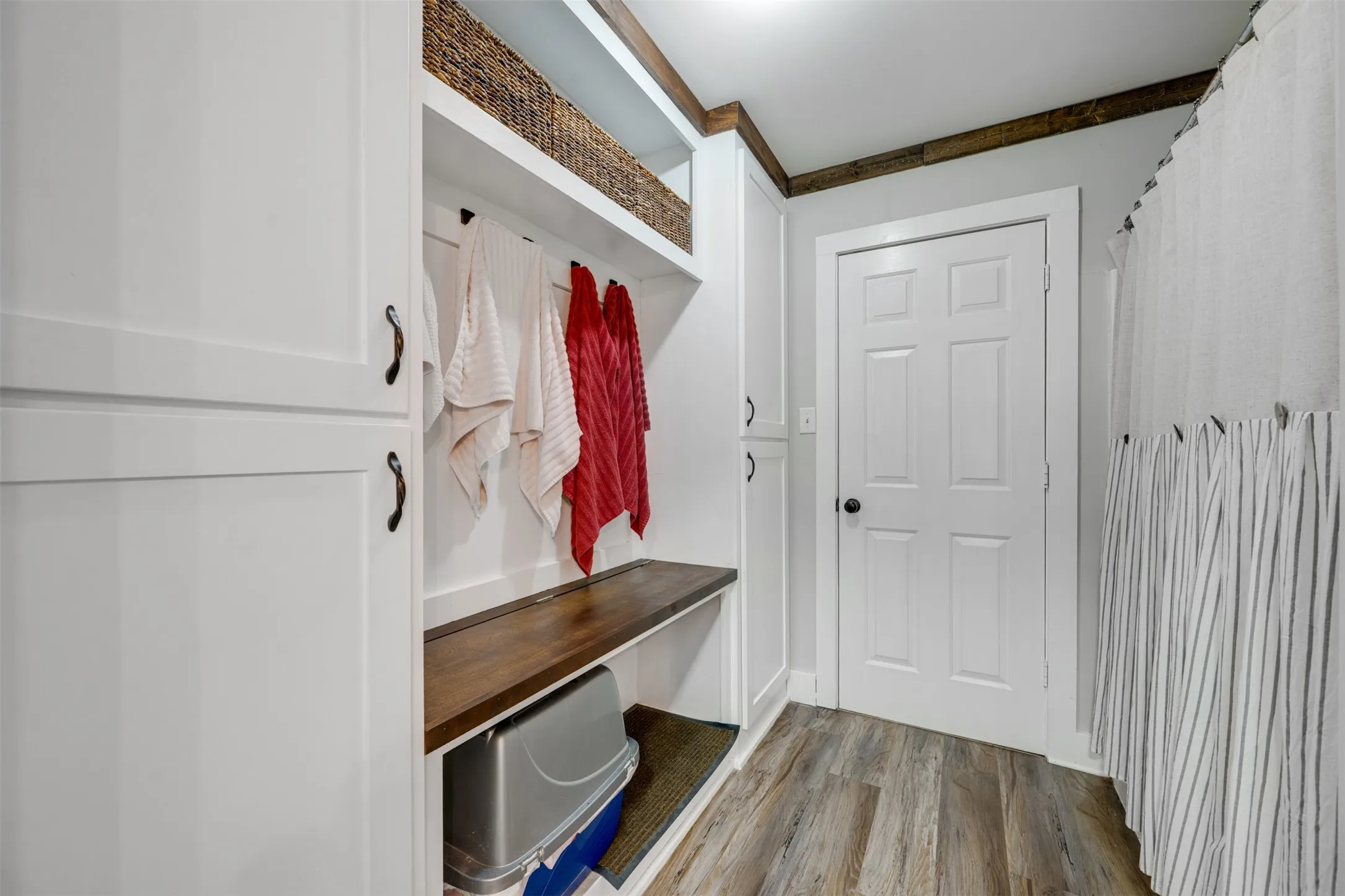 Built-in storage solutions, wood-finish flooring, white paneled door, and dark wood trim