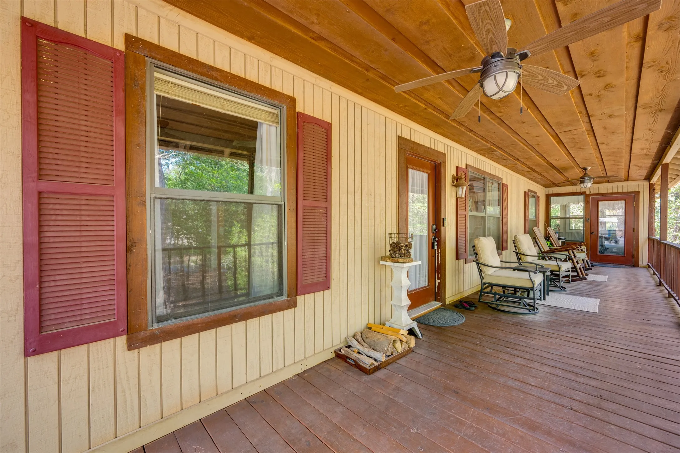 Expansive covered porch with wood-finish flooring, wood plank ceiling, and ceiling fans