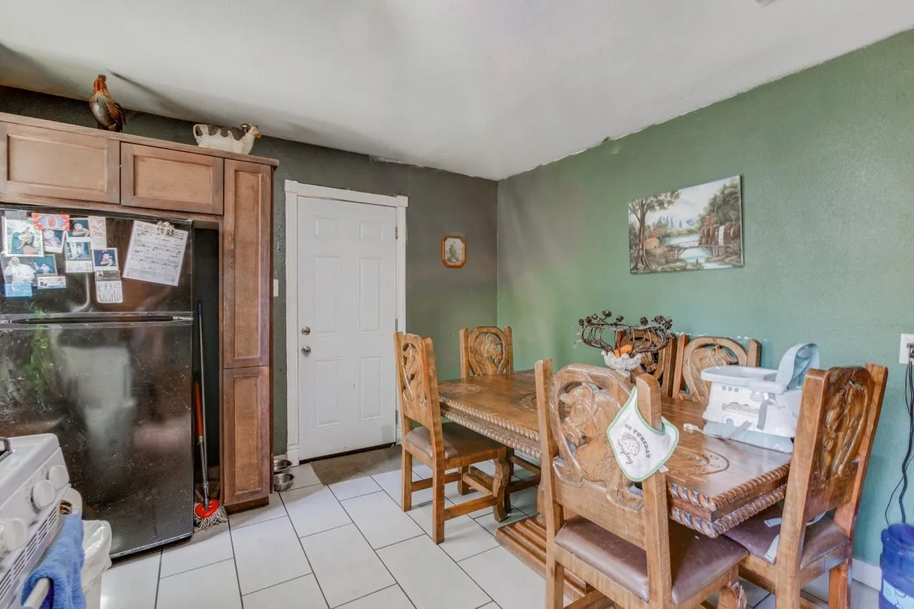 White tile flooring, wood-finish cabinetry, paneled white door, and textured wall finish