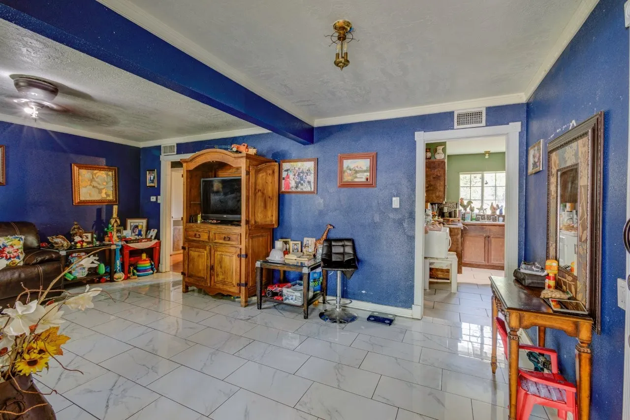 White large format tile flooring and a cased opening leading to an additional space with wood cabinetry