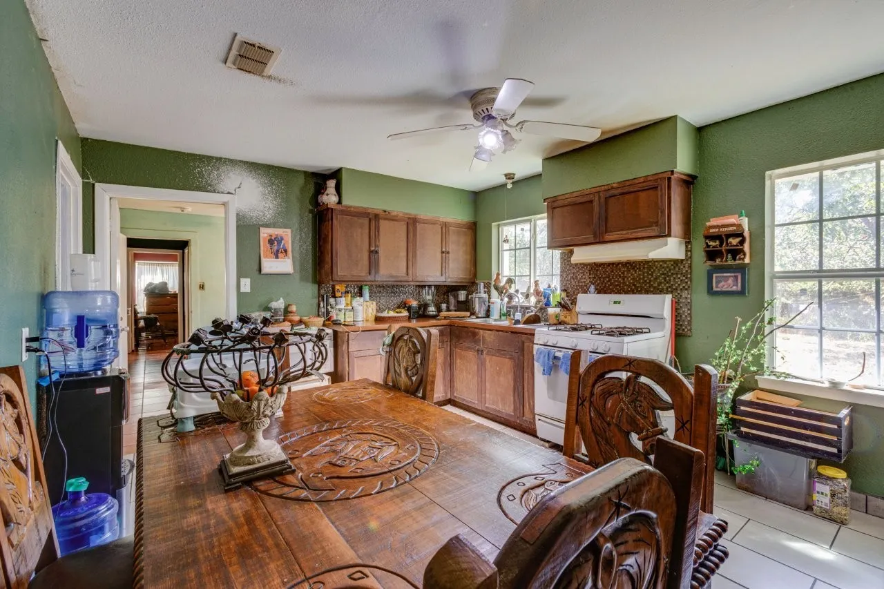 Kitchen featuring wood cabinetry, a built-in range, a ceiling fan, and two windows