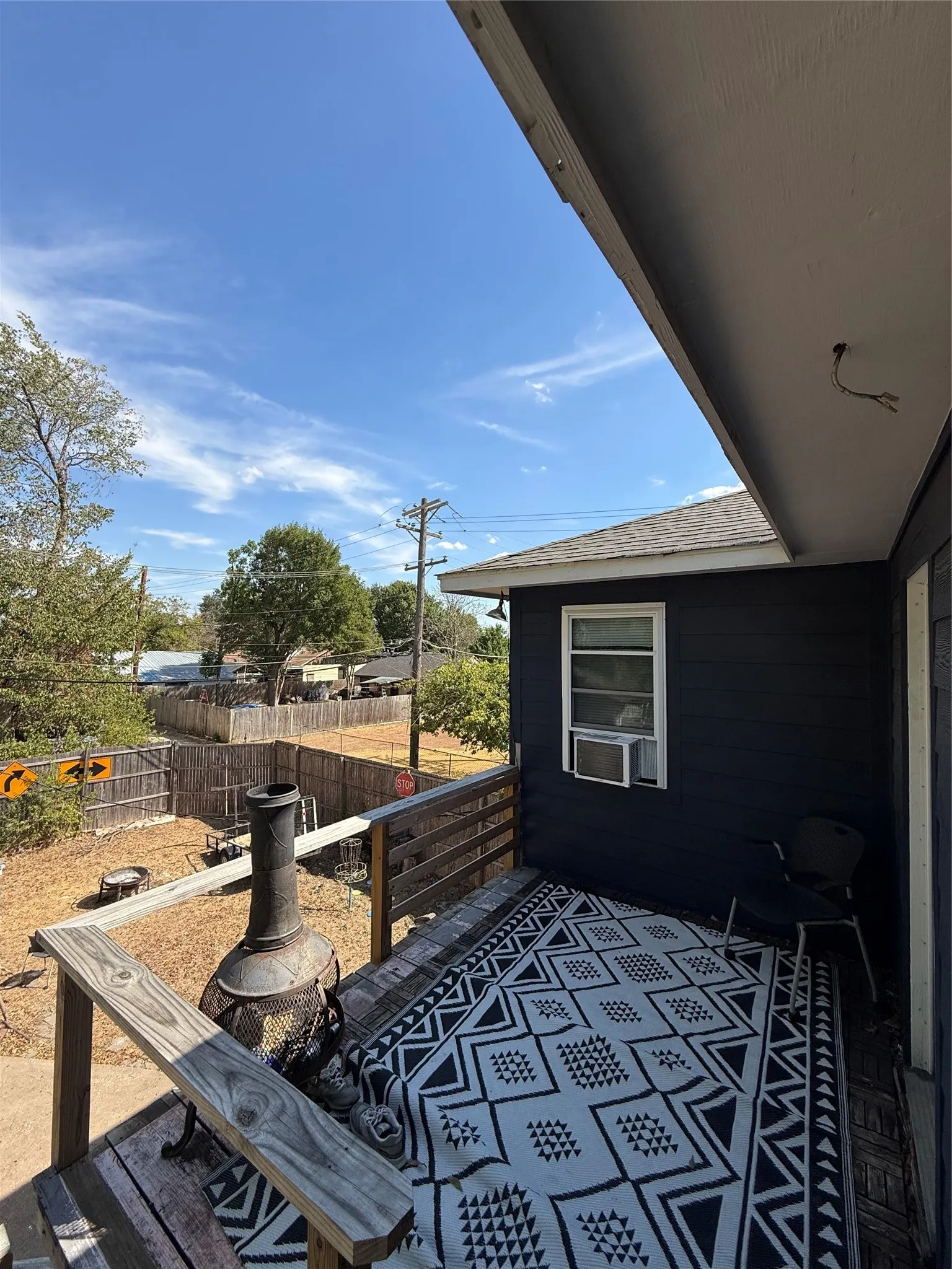 Outdoor deck with wood railings, dark exterior siding, and a window air conditioning unit