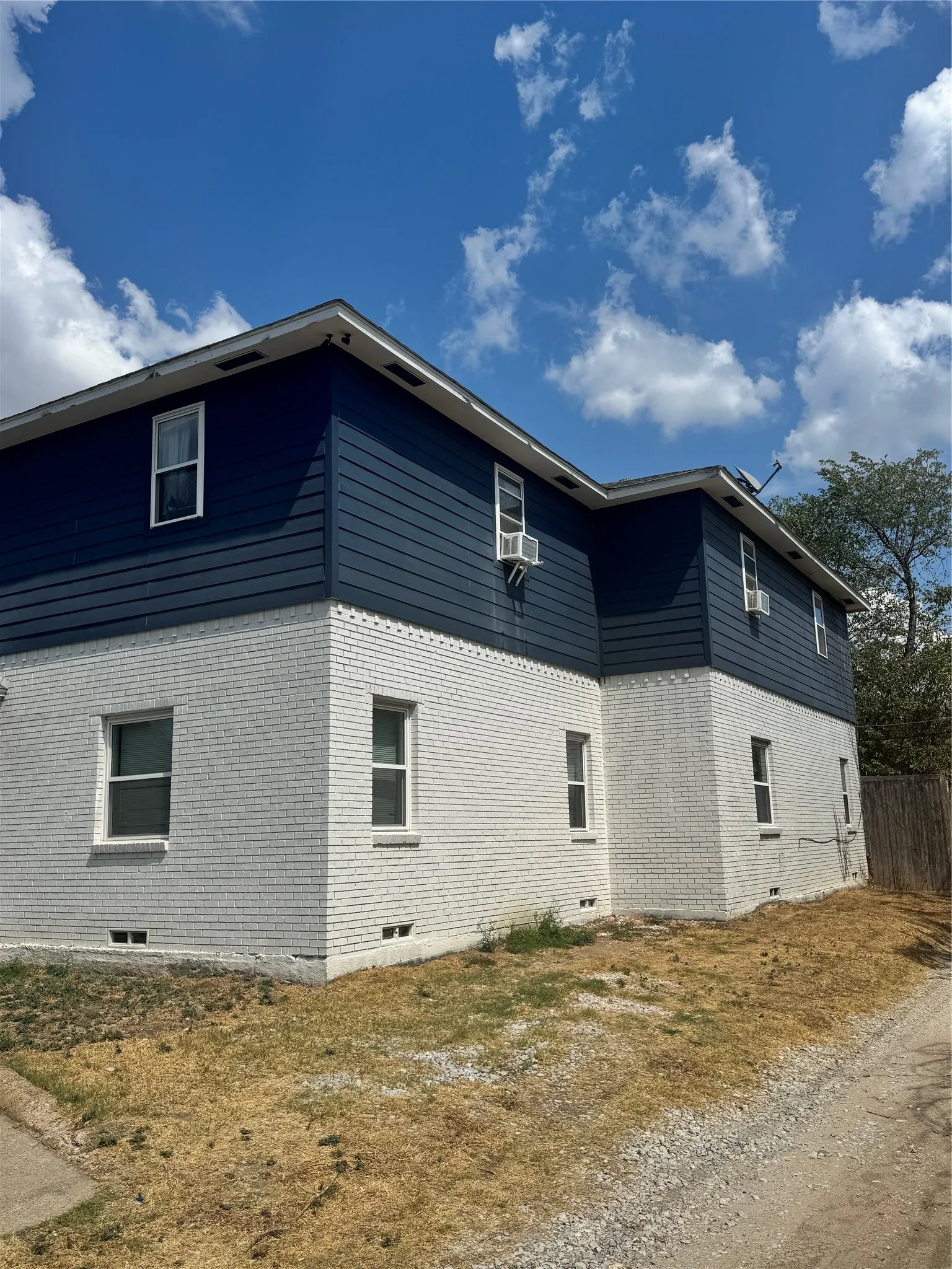 Two-story exterior featuring white painted brick and dark blue horizontal siding
