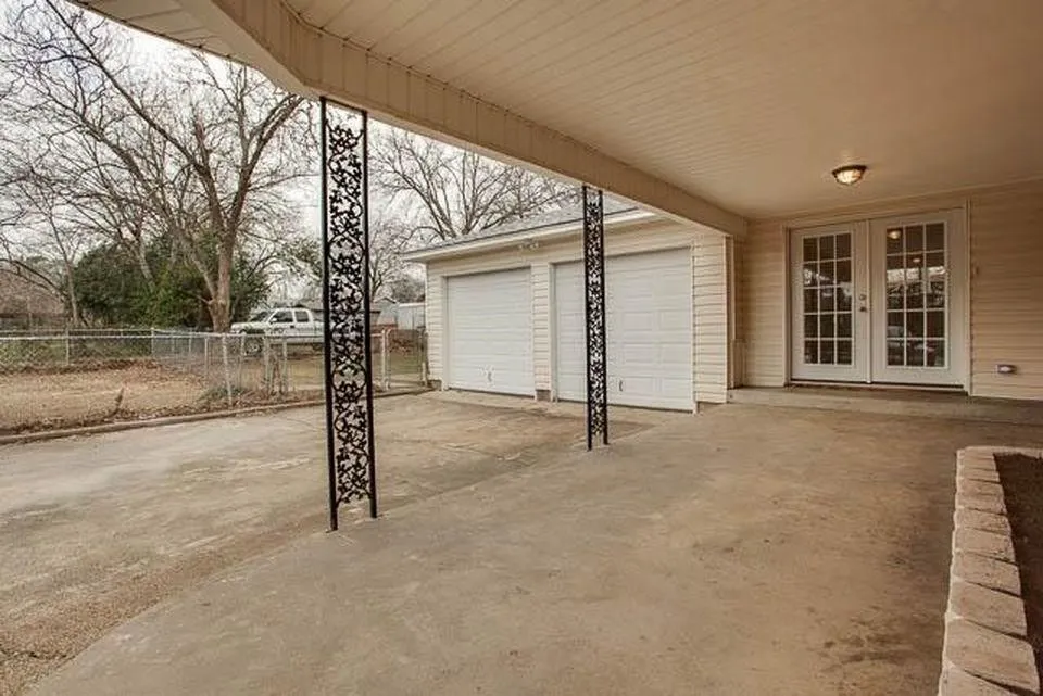 Covered concrete patio featuring decorative metal columns and built-in overhead lighting