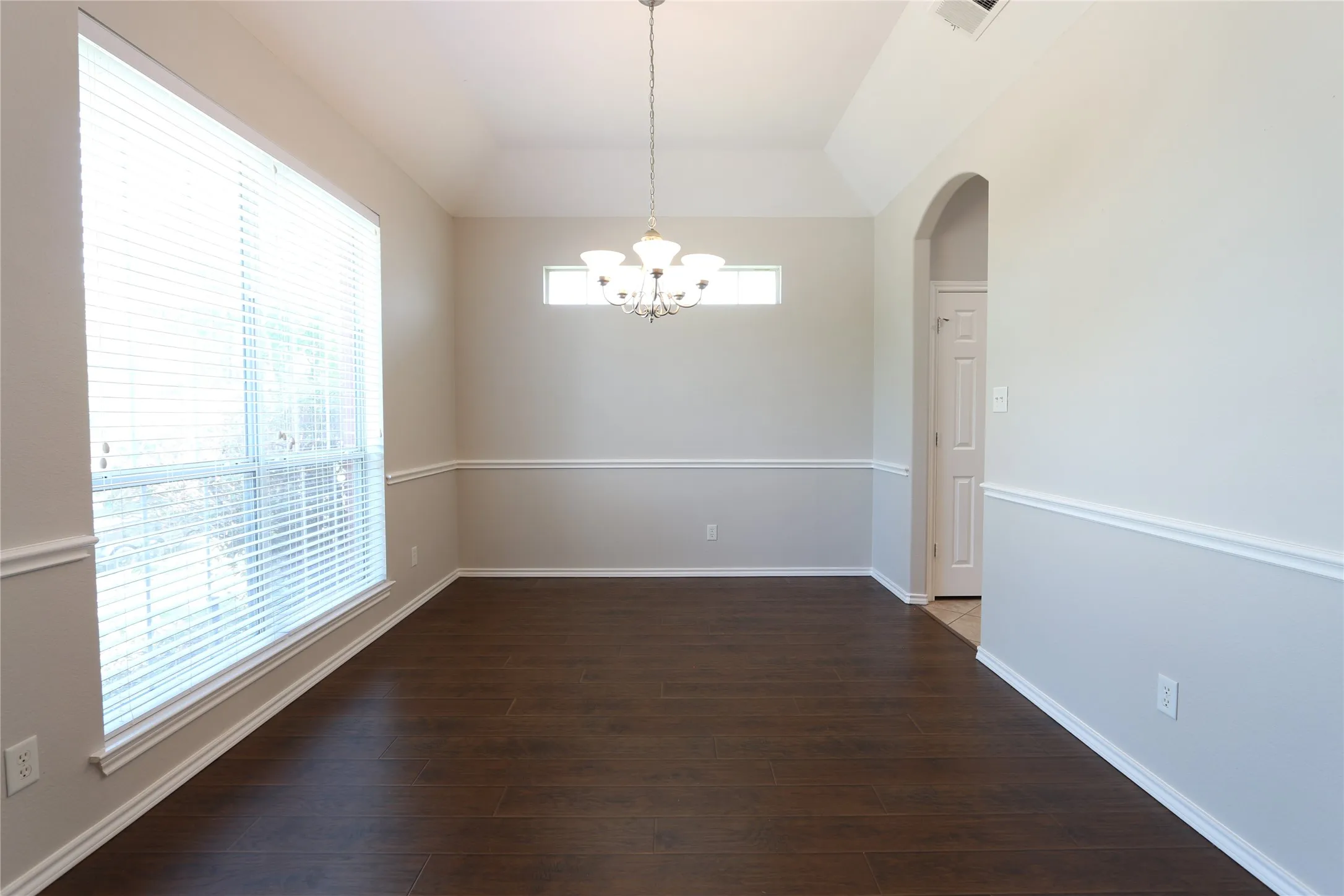 Unfurnished dining area featuring dark hardwood / wood-style flooring, a wealth of natural light, and a chandelier