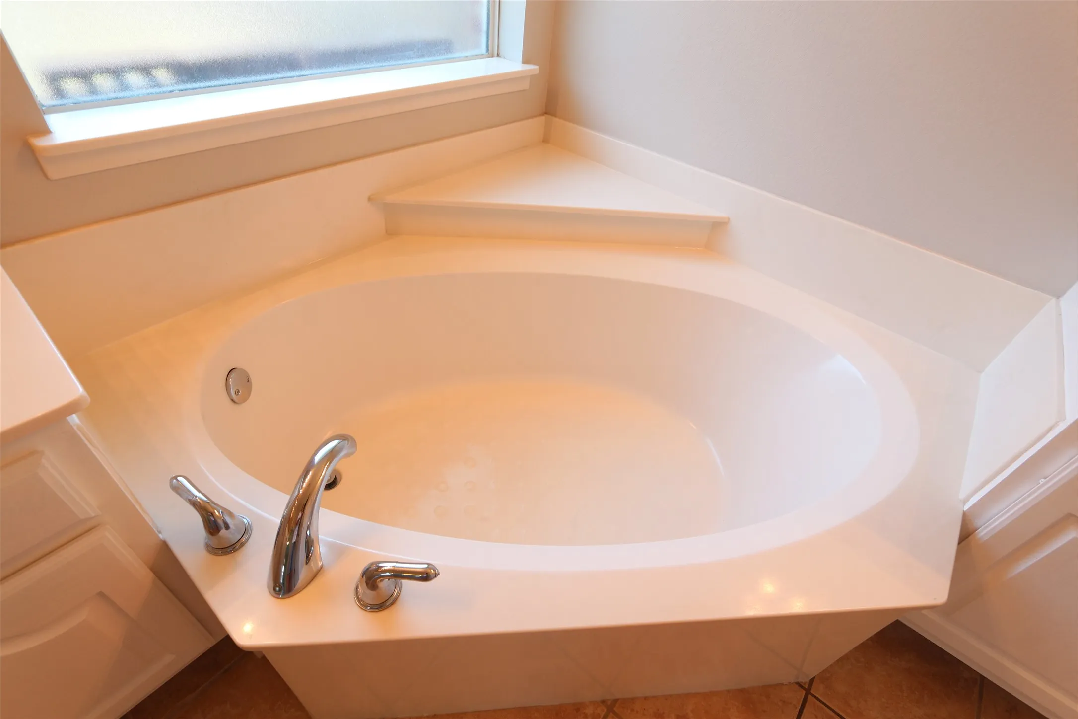 Bathroom with tile flooring, a healthy amount of sunlight, and a bath to relax in