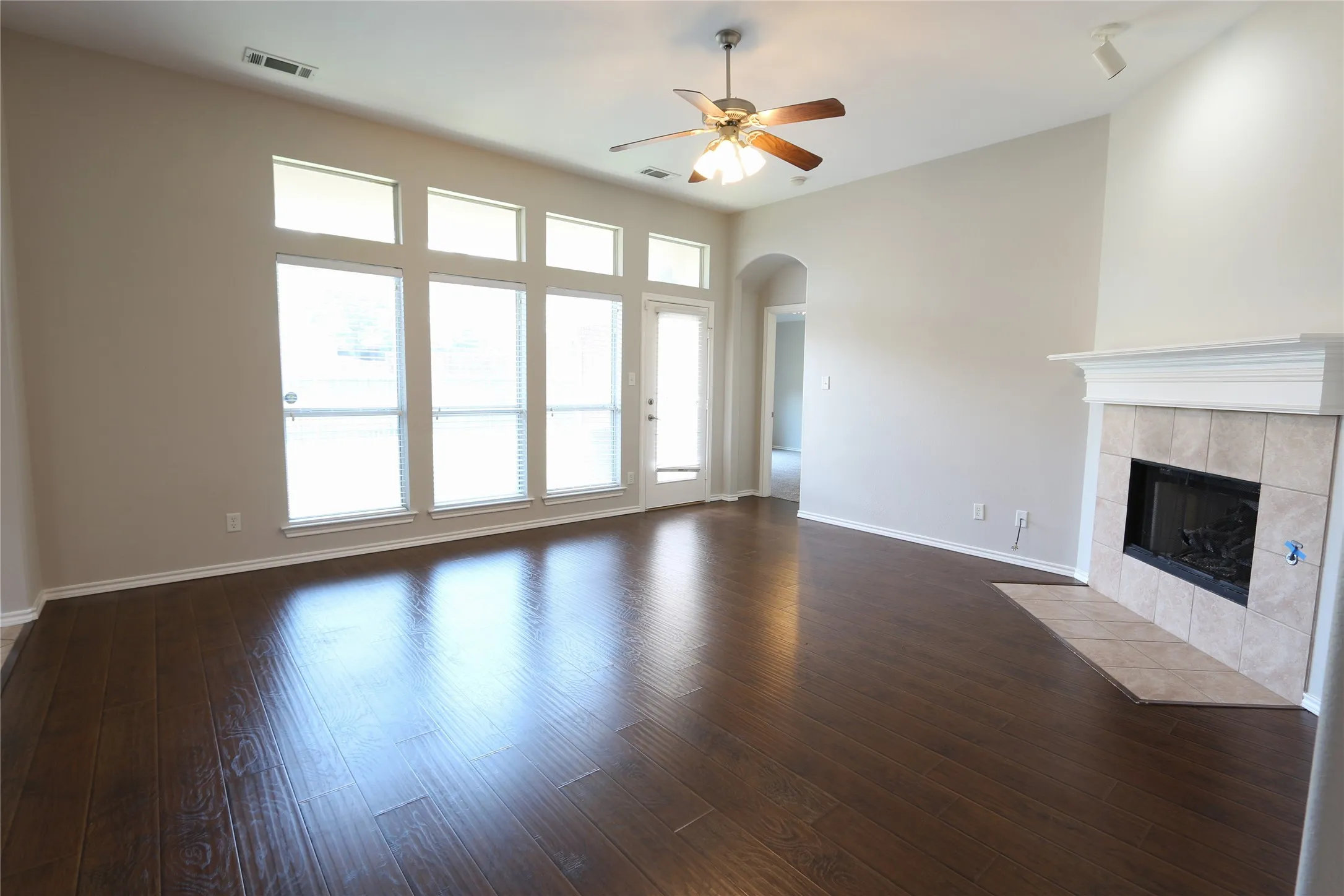 Unfurnished living room with a tile fireplace, ceiling fan, and dark hardwood / wood-style flooring