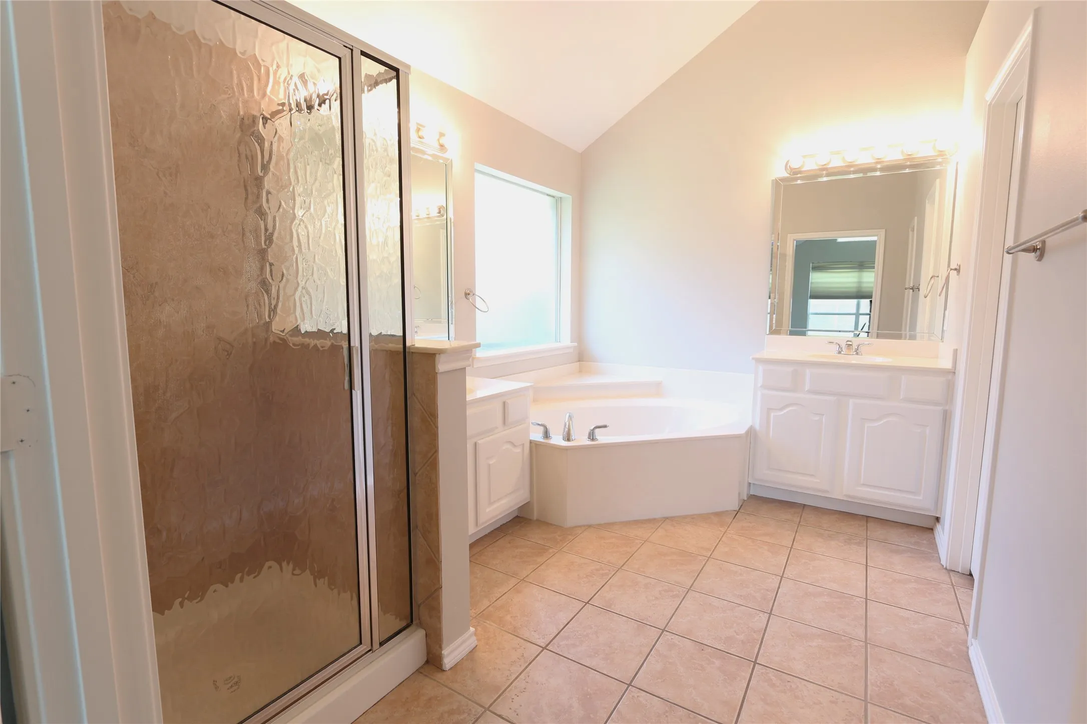 Bathroom with a wealth of natural light, independent shower and bath, lofted ceiling, and vanity