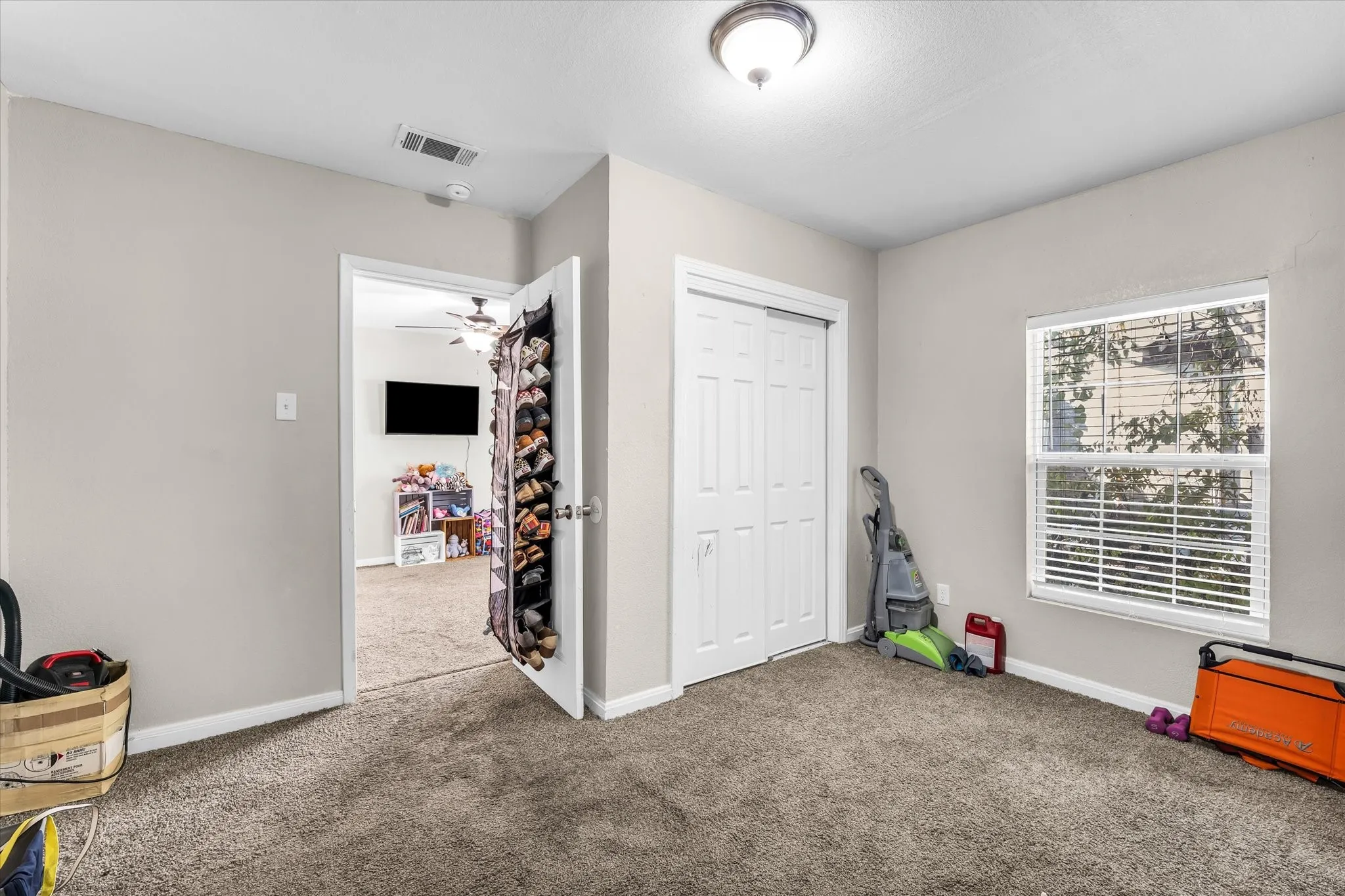 Carpeted room with a single window, white window blinds, and a bi-fold closet door