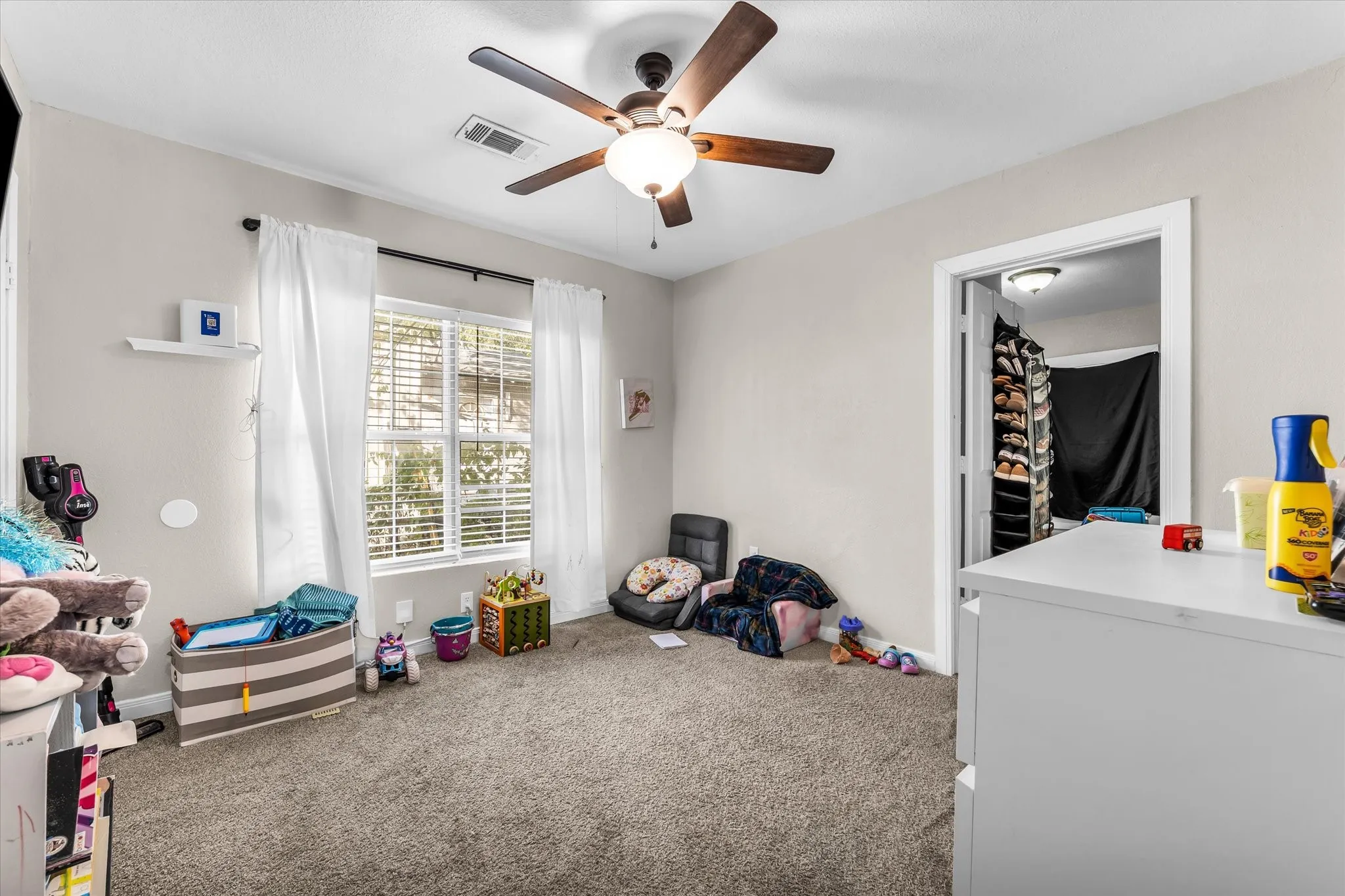 Carpeted room with a ceiling fan, a window with blinds, and an open doorway to a closet