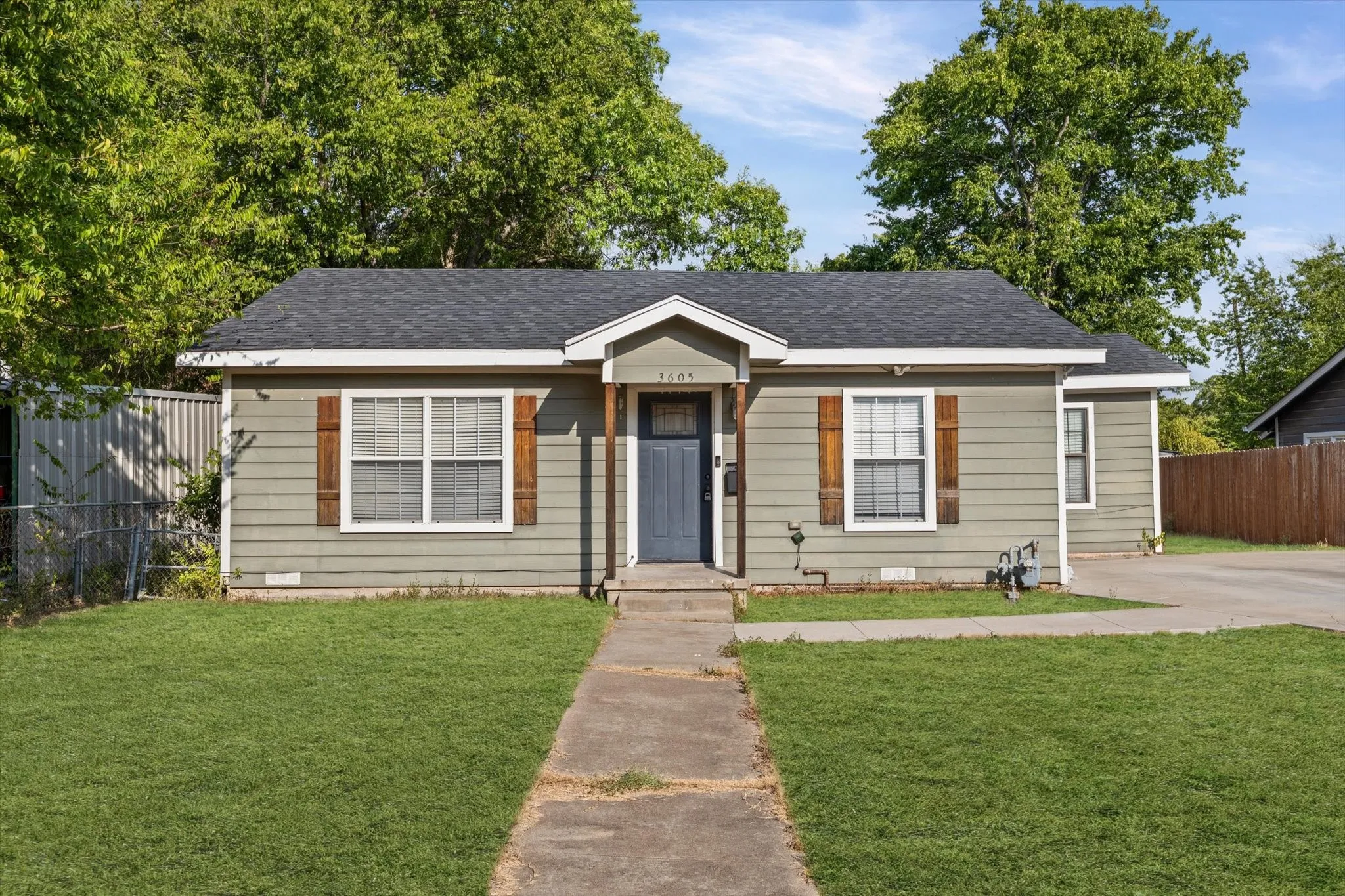 Front exterior with horizontal siding, dark asphalt shingle roof, and a concrete walk-up