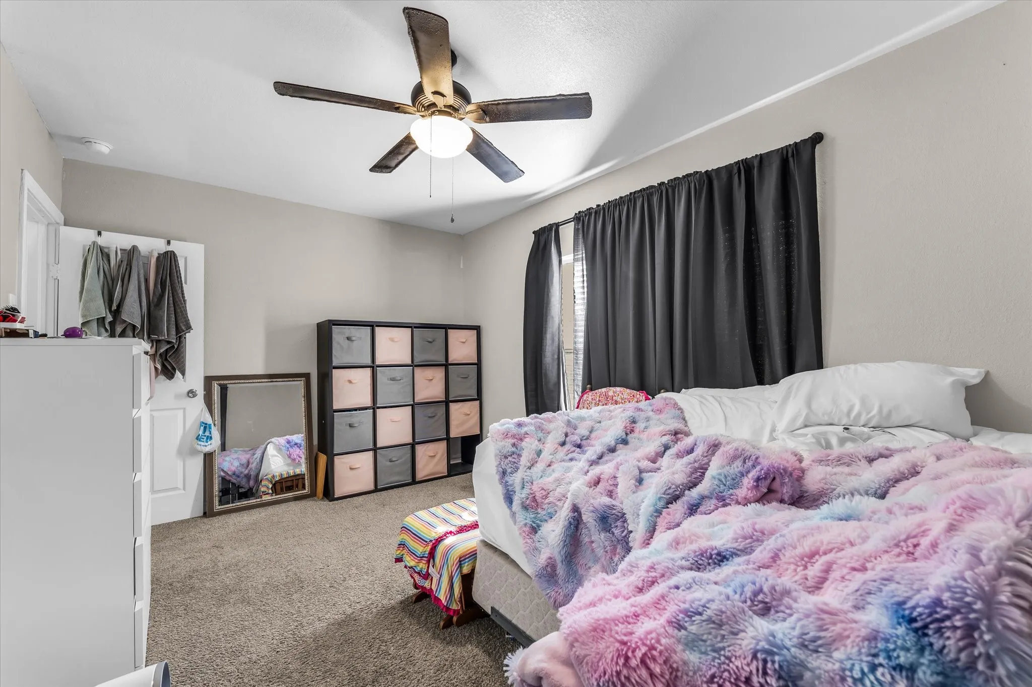 Carpeted flooring, ceiling fan with integrated lighting, window with dark drapes, light neutral wall paint