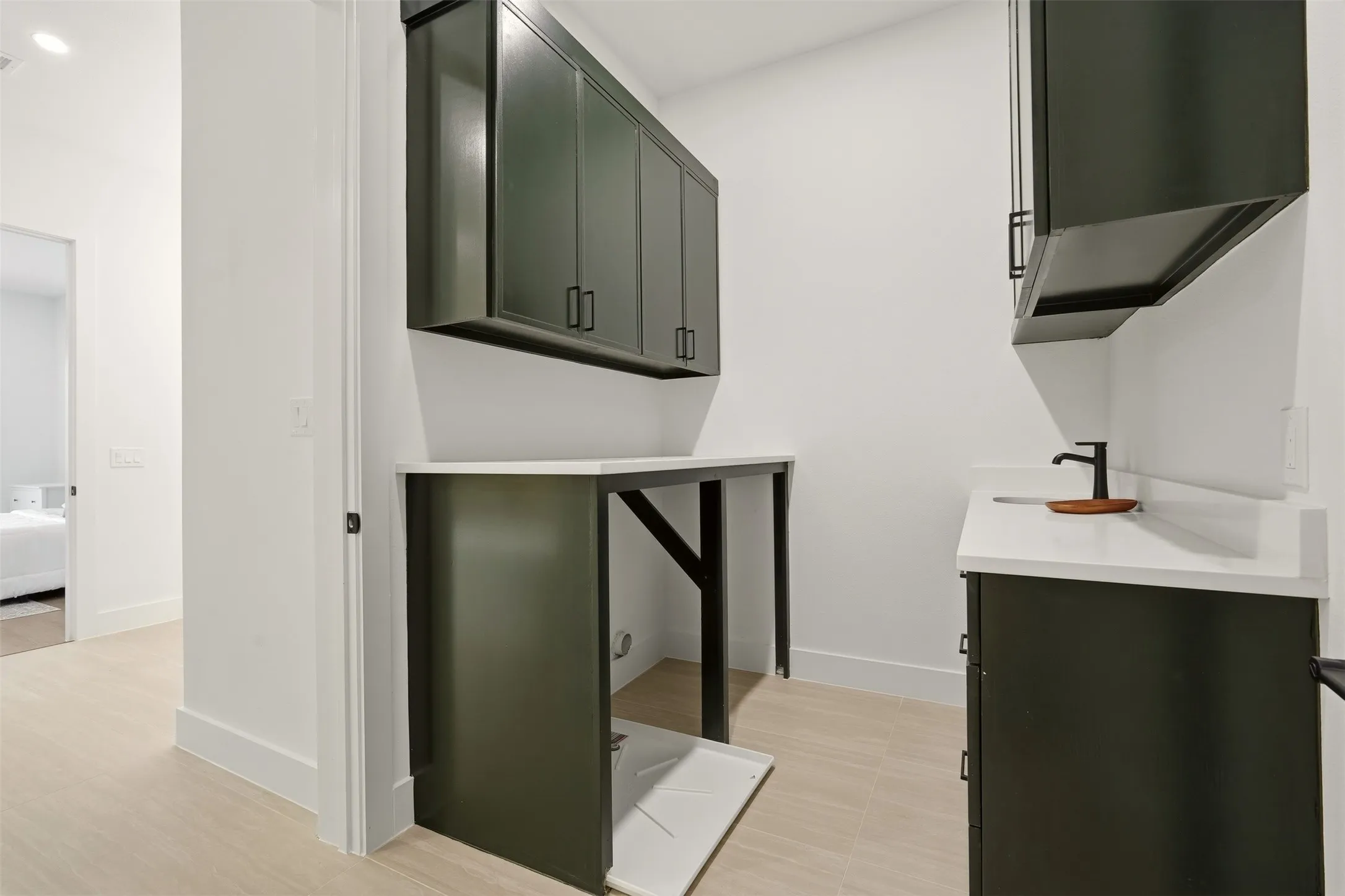 Dark-toned cabinetry with matte black hardware, white countertops, and a black faucet