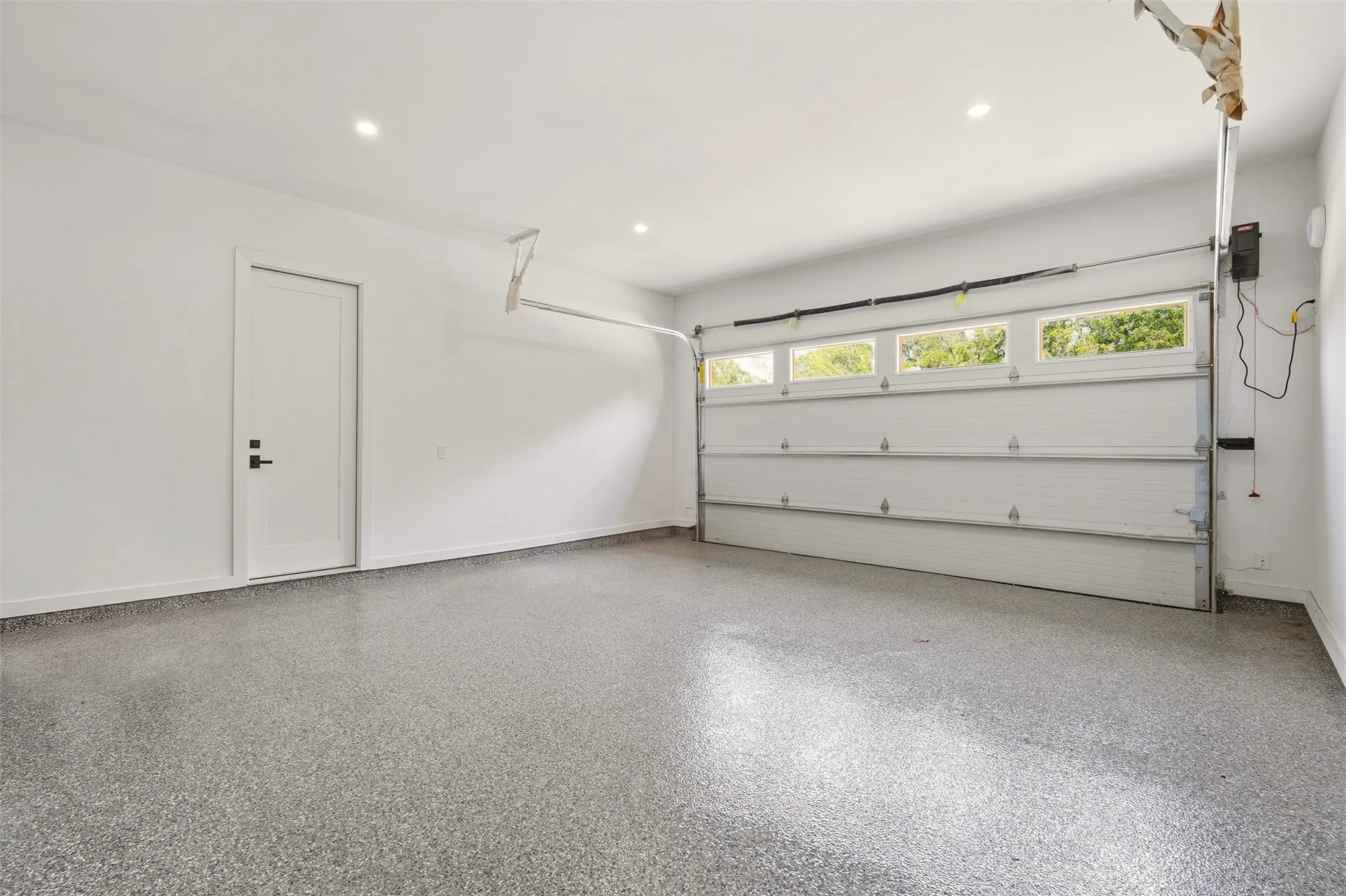 Epoxy-coated flooring, recessed lighting, and a white overhead garage door with upper windows
