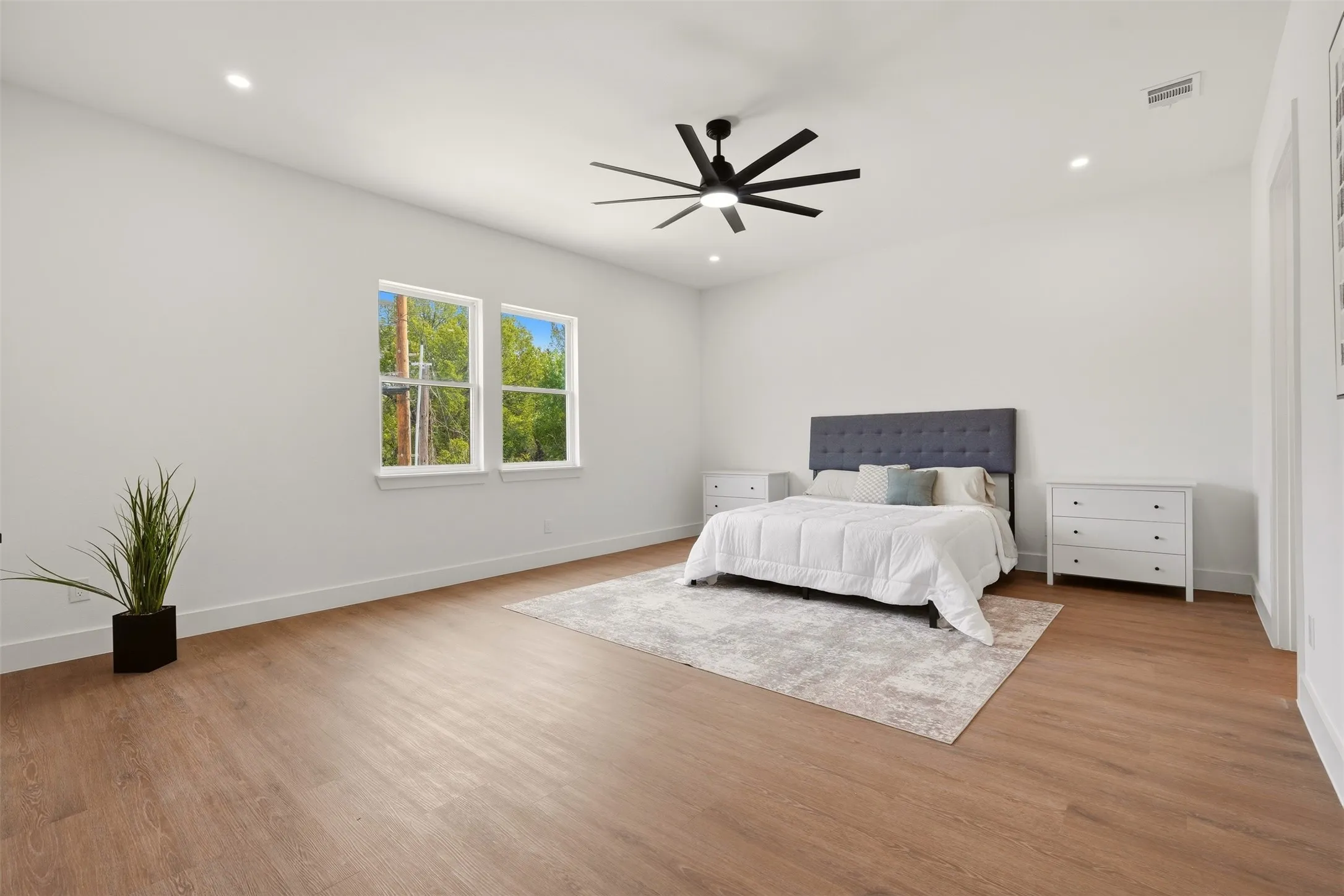 Spacious room with wood-finish flooring, recessed lighting, and a modern ceiling fan