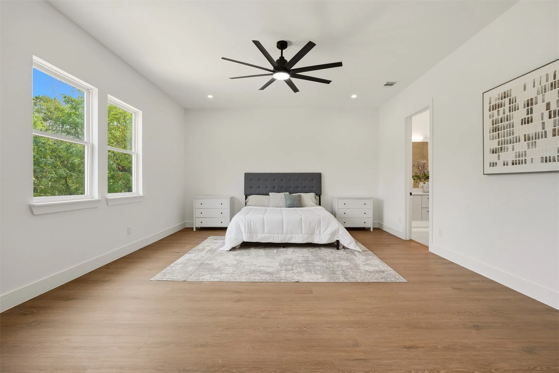 Spacious room featuring wood-finish flooring, recessed lighting, and a modern ceiling fan