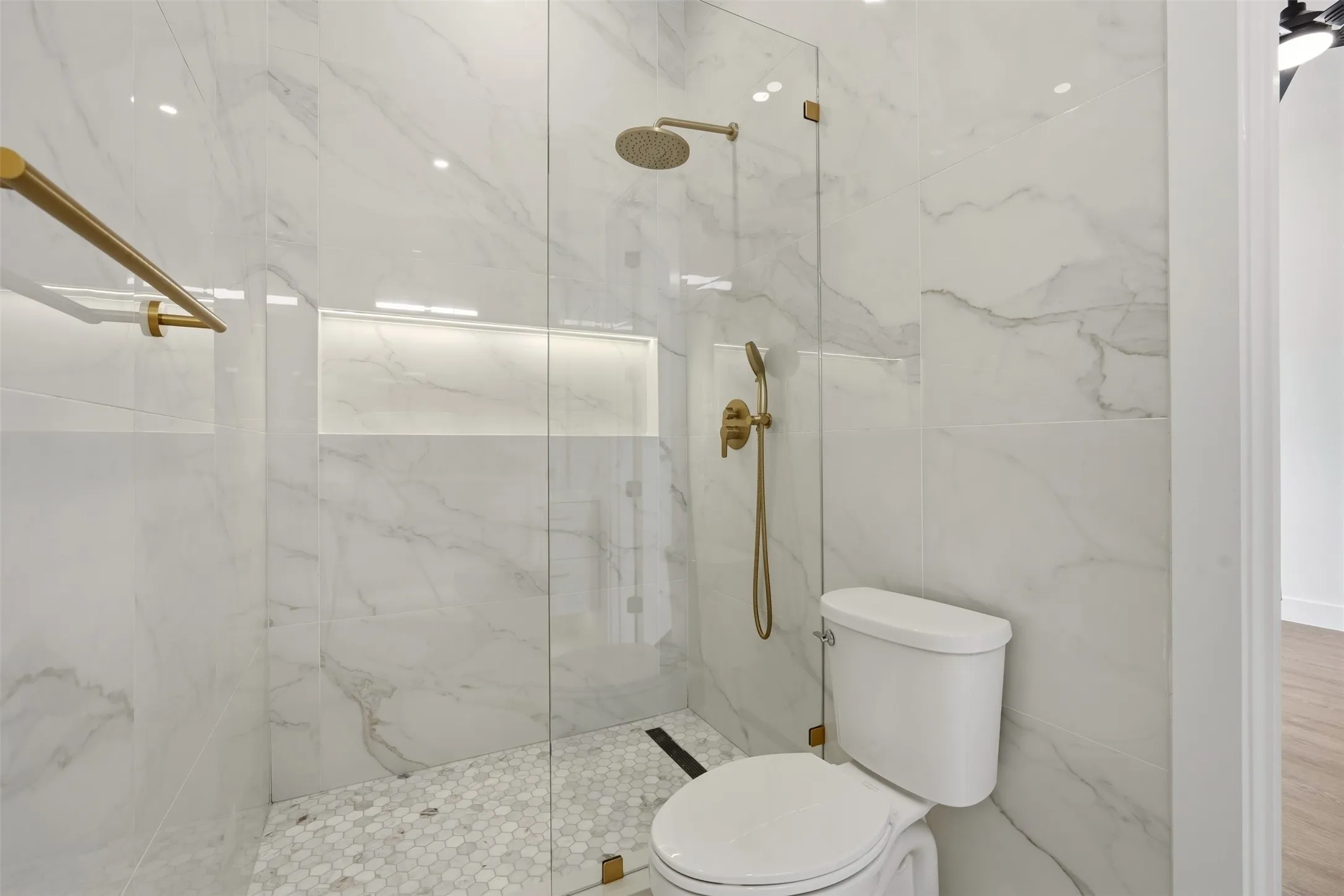 Walk-in shower with full-height large format wall tile, rain shower head, and built-in niche